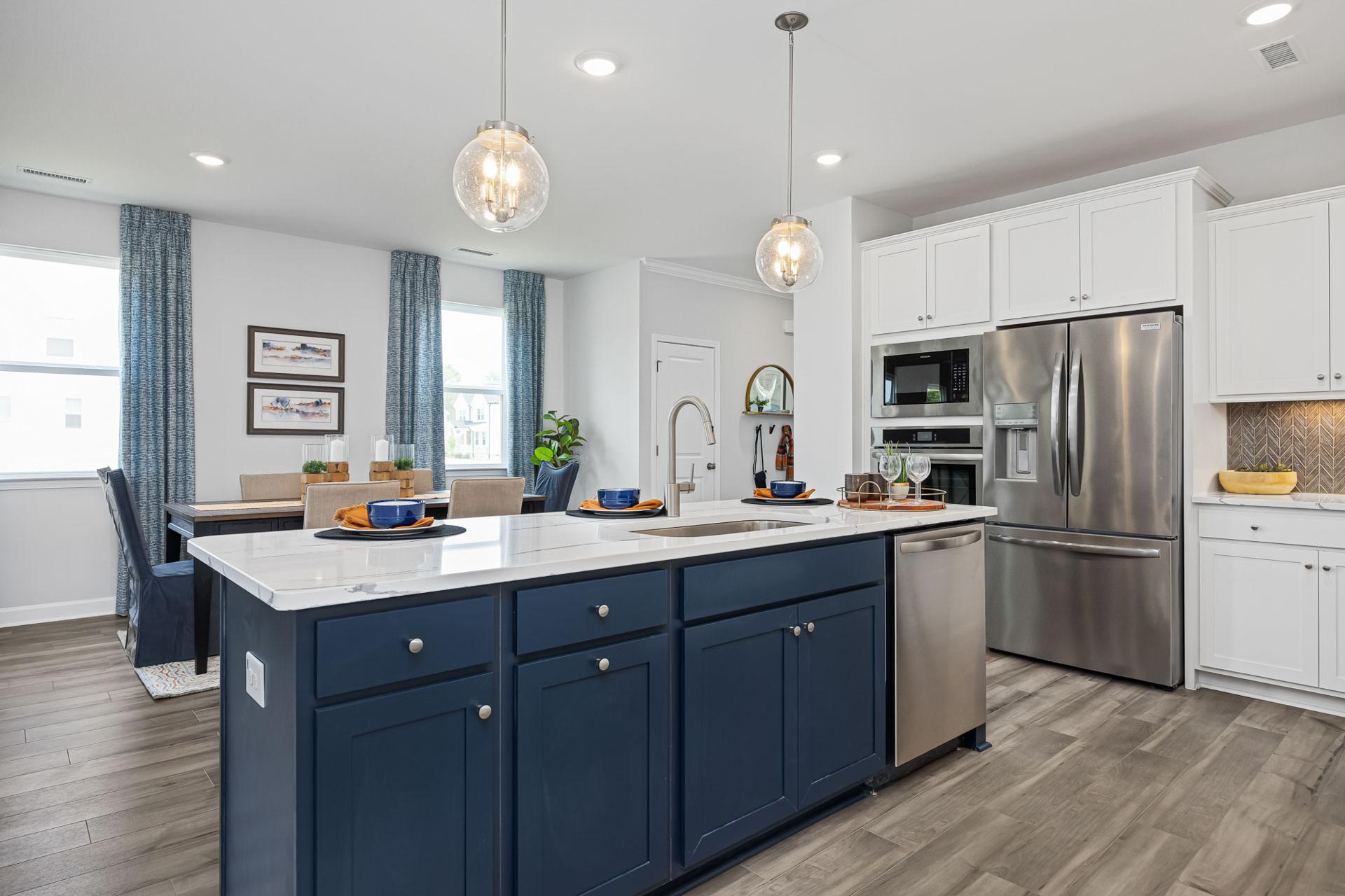 Spacious modern kitchen with navy island, white cabinets, stainless steel appliances, and hardwood floors at Beverly Place in Four Oaks NC