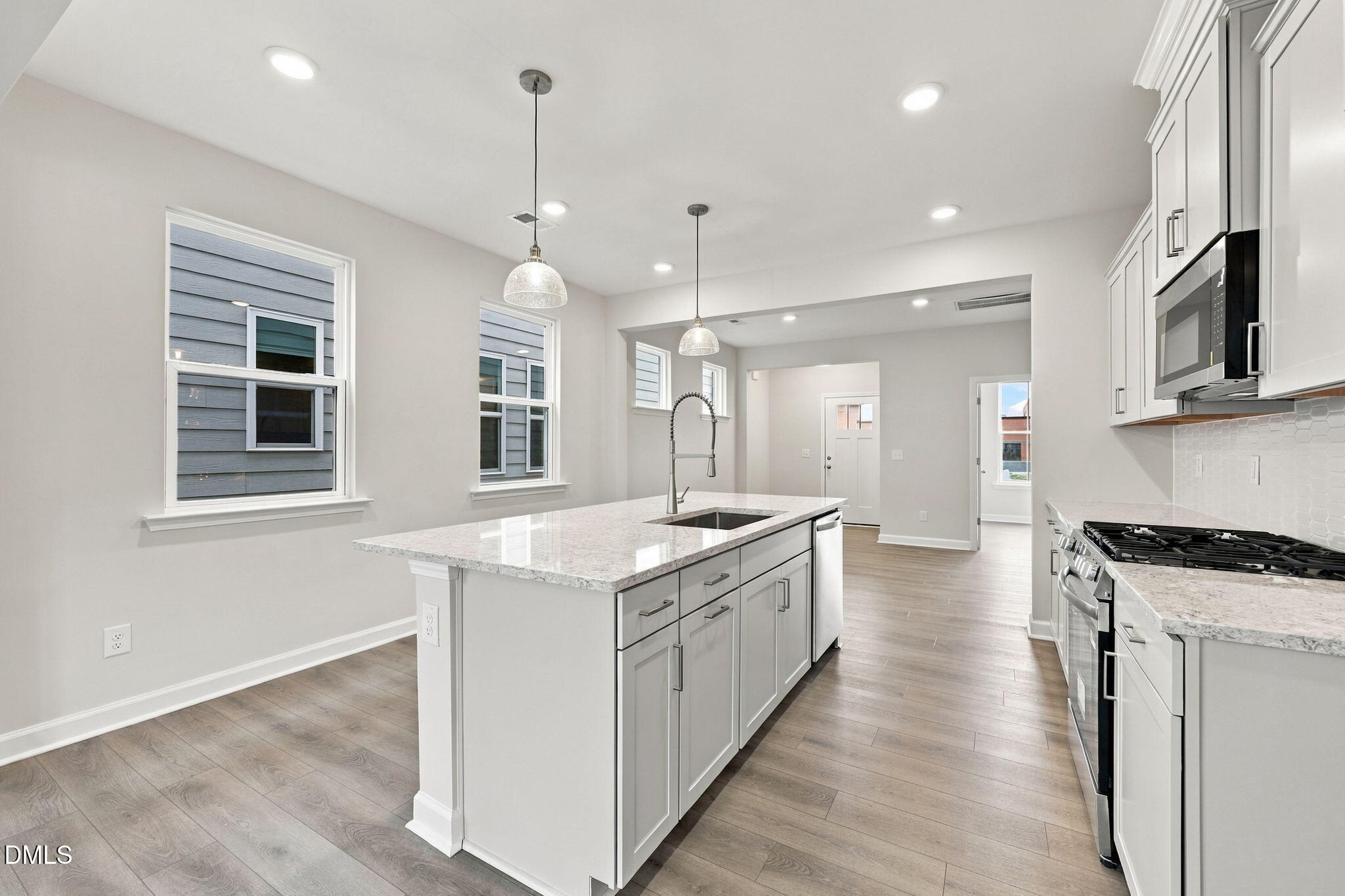 Bright white kitchen with island, granite countertops, and gas range in Davidson Homes The Alexander B, Knightdale, NC