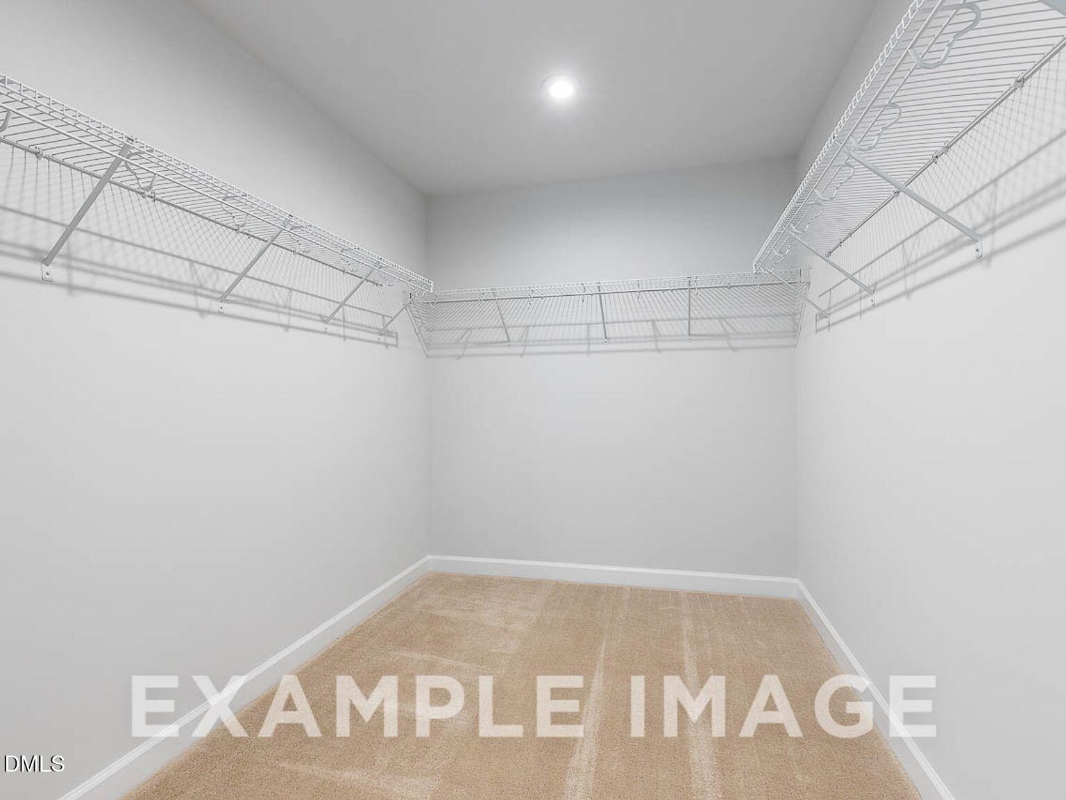 Spacious walk-in closet featuring white wire shelving and beige carpet in master suite, Davidson Homes The Chestnut B, Lillington, NC