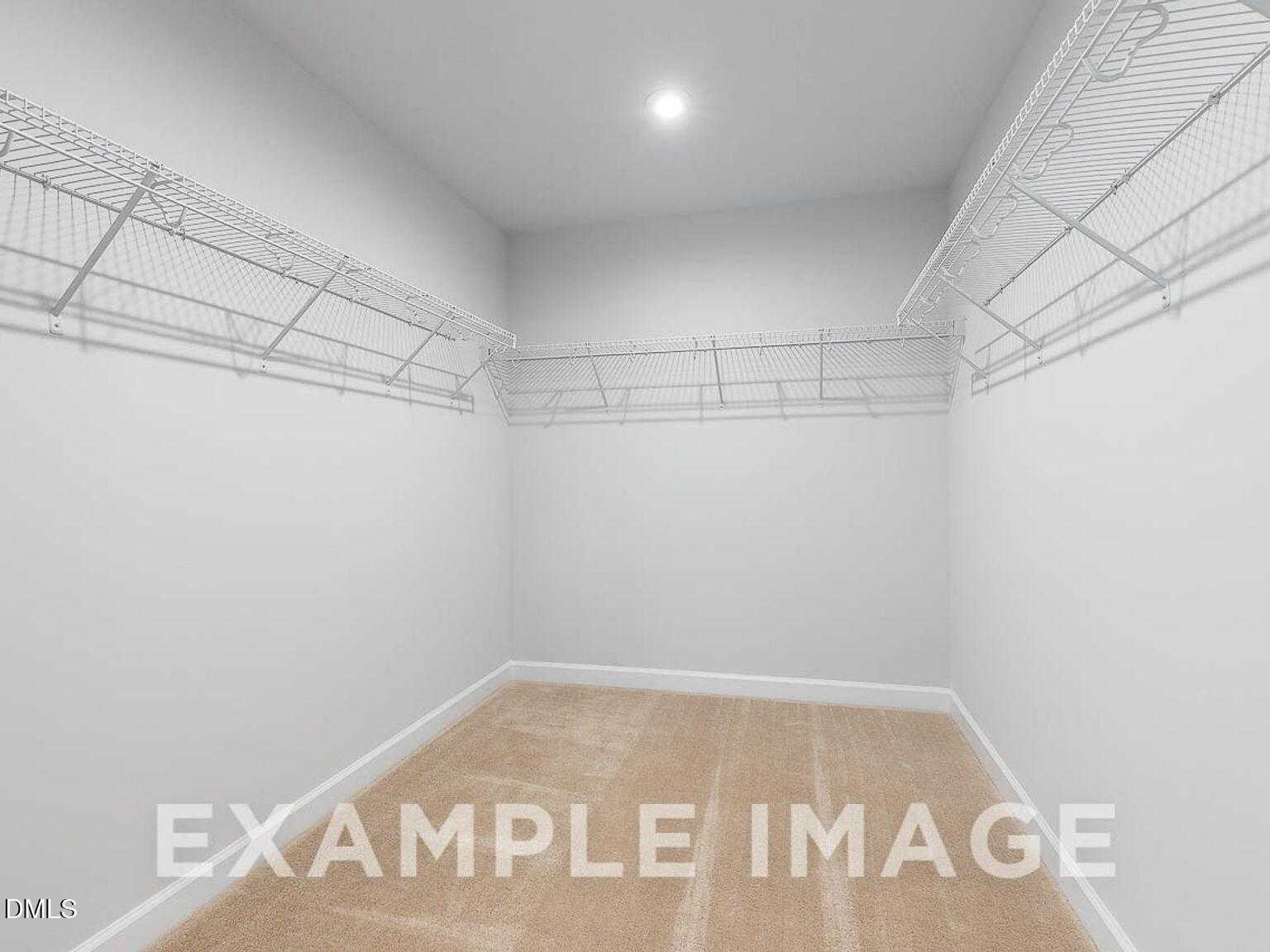 Spacious walk-in closet featuring white wire shelving and beige carpet in master suite, Davidson Homes The Chestnut B, Lillington, NC