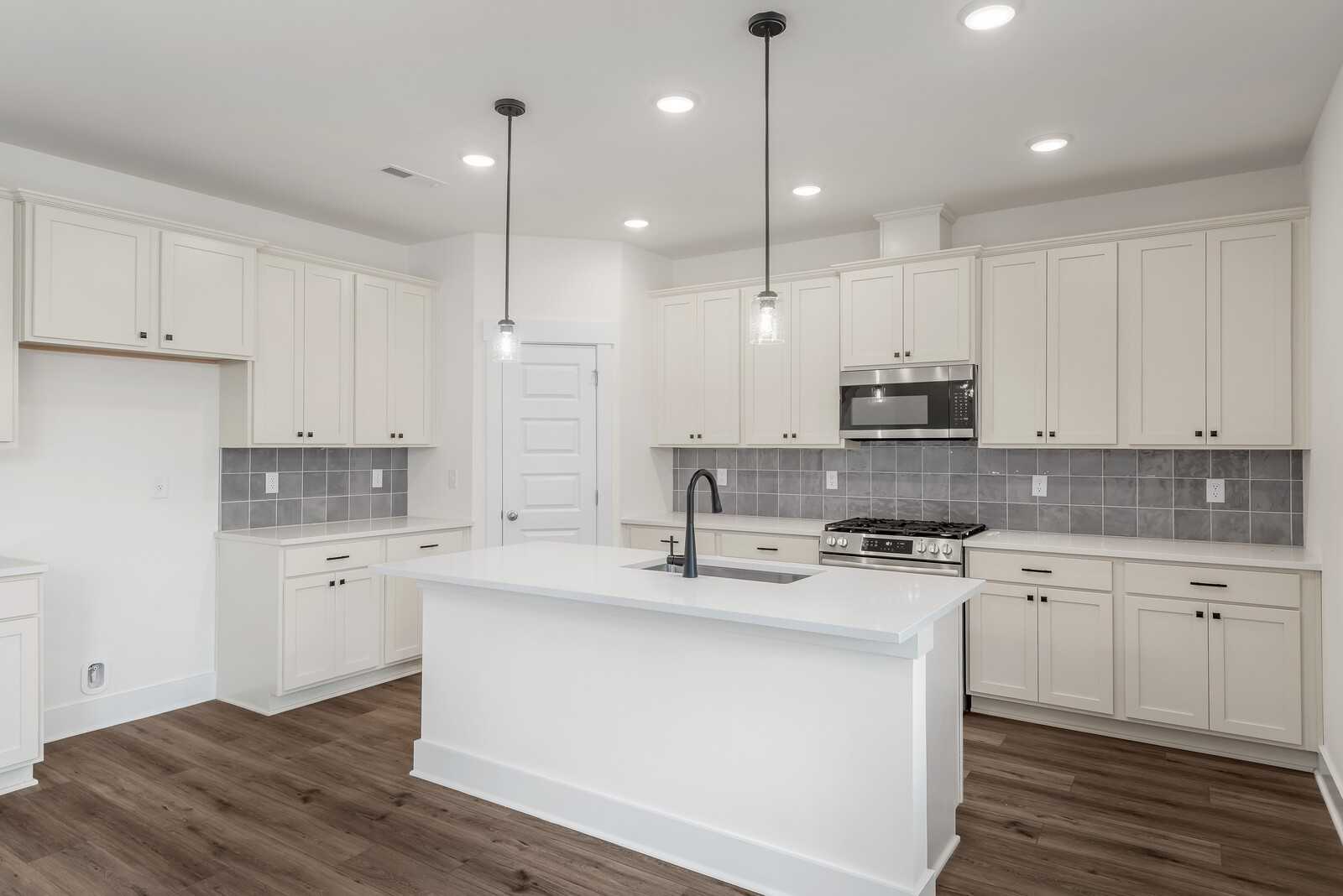 Modern white shaker kitchen with large island, subway tile backsplash, stainless appliances in The Logan C by Davidson Homes, Gallatin, TN