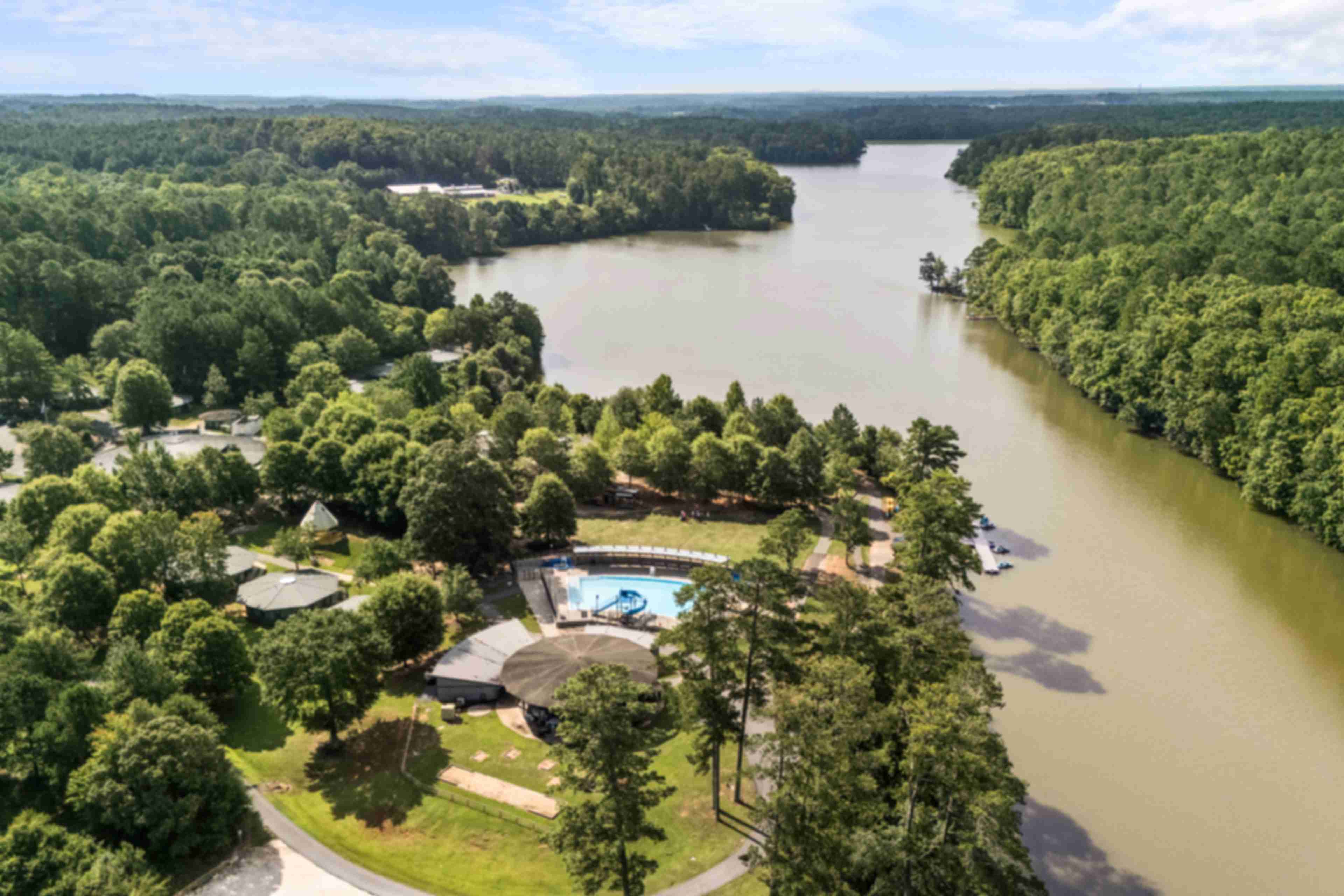 Aerial view of Lake Shore community in Winder GA featuring resort-style pool, clubhouse, lush forest, and serene lakefront