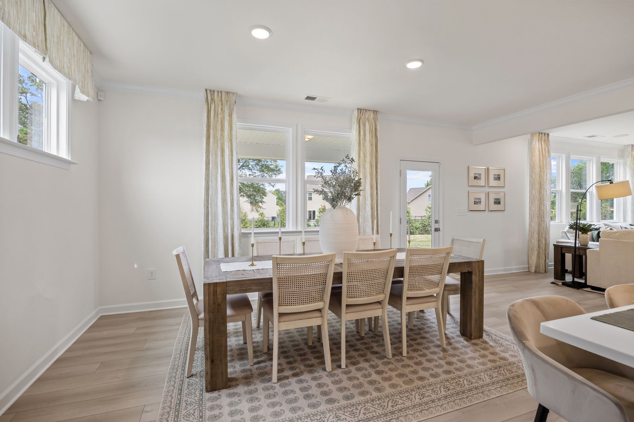 Bright dining room in Springvale South by Davidson Homes with wood table, cane chairs, and light hardwood floors.