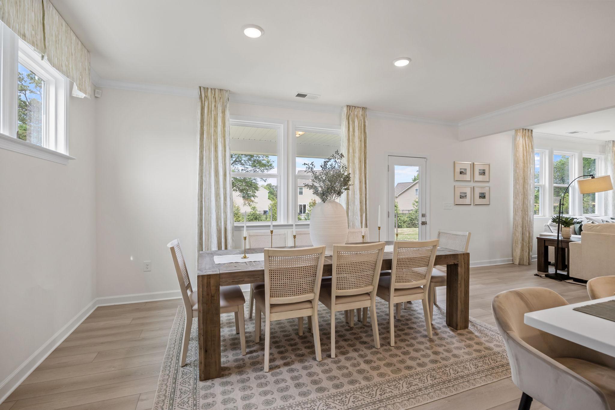 Bright dining room in Springvale South by Davidson Homes with wood table, cane chairs, and light hardwood floors.