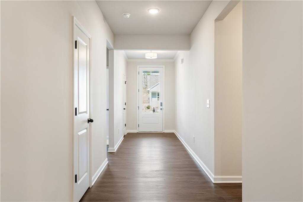 Bright hallway with hardwood floors, white paneled doors, and flush-mount lighting in The Daphne B home, Loganville, GA