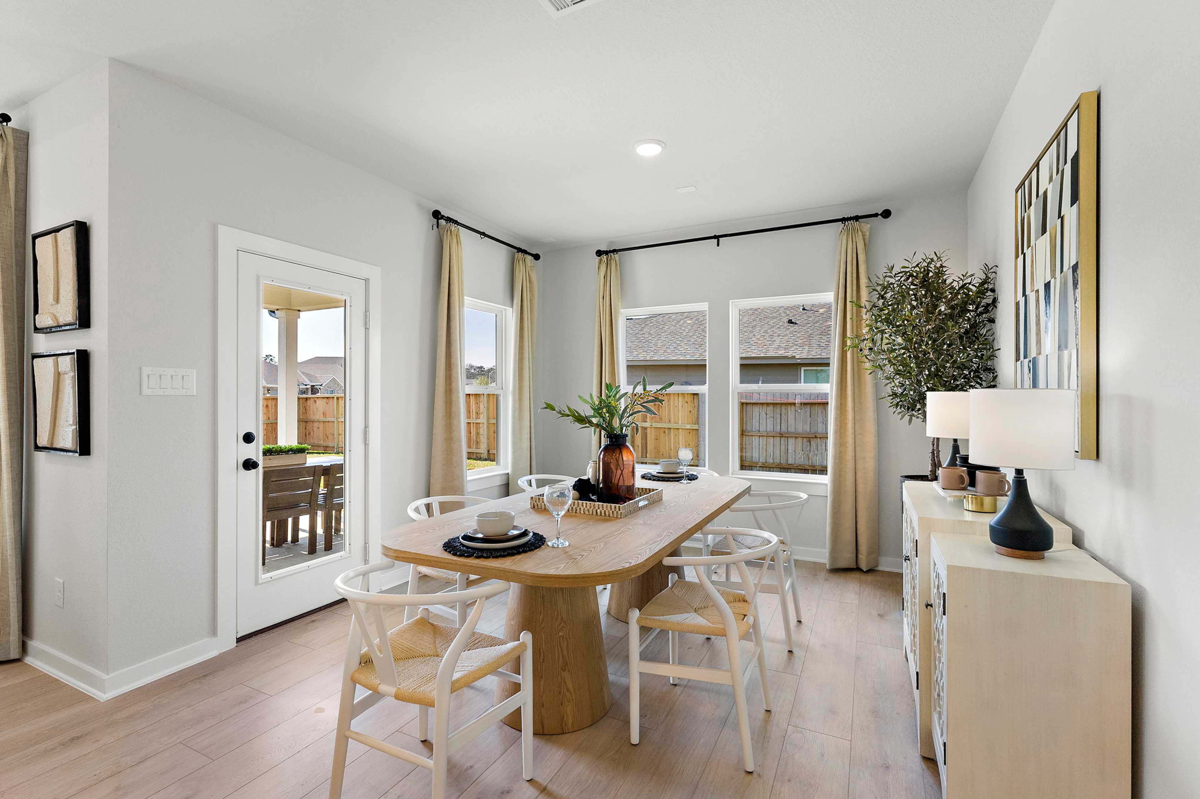 Modern dining room in Sundance Cove Crosby TX with oak table white chairs plants French doors and hardwood floors