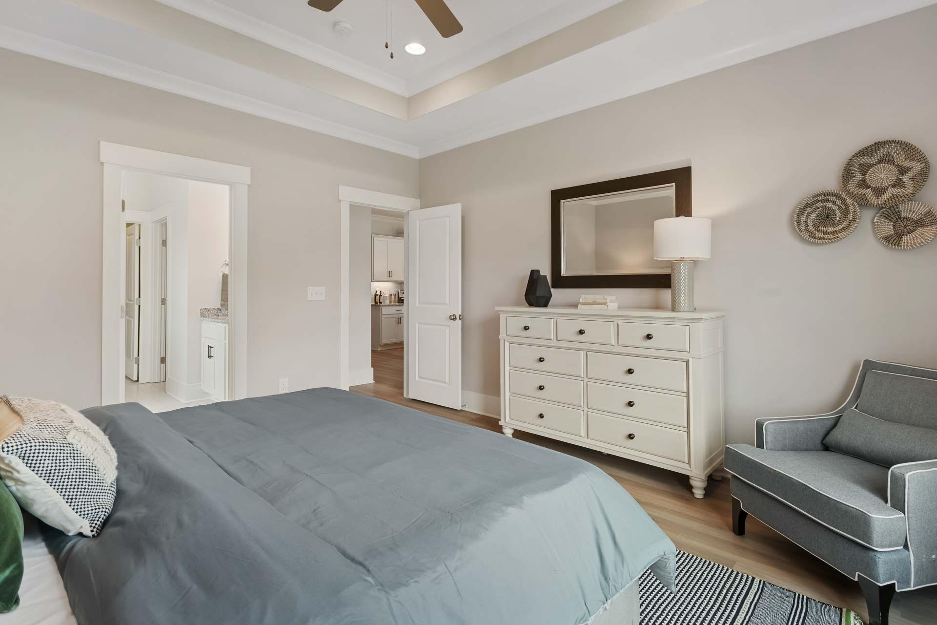 Spacious primary bedroom at Durham Farms in Harvest Alabama with king bed, hardwood floors, en-suite bath