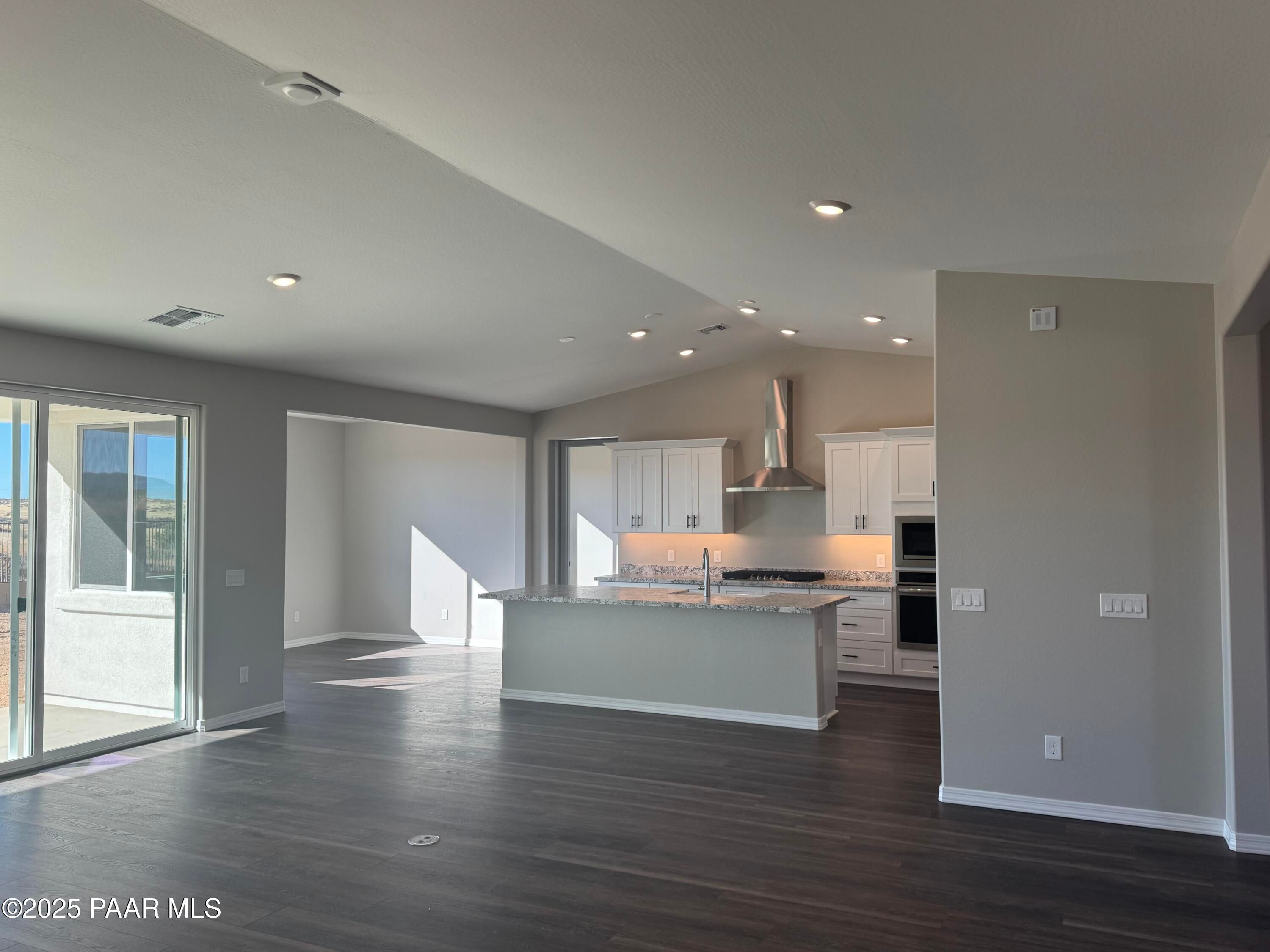 Modern open kitchen with white cabinets, large island sink, stainless appliances in The Monarch E, Westwood, Prescott, AZ