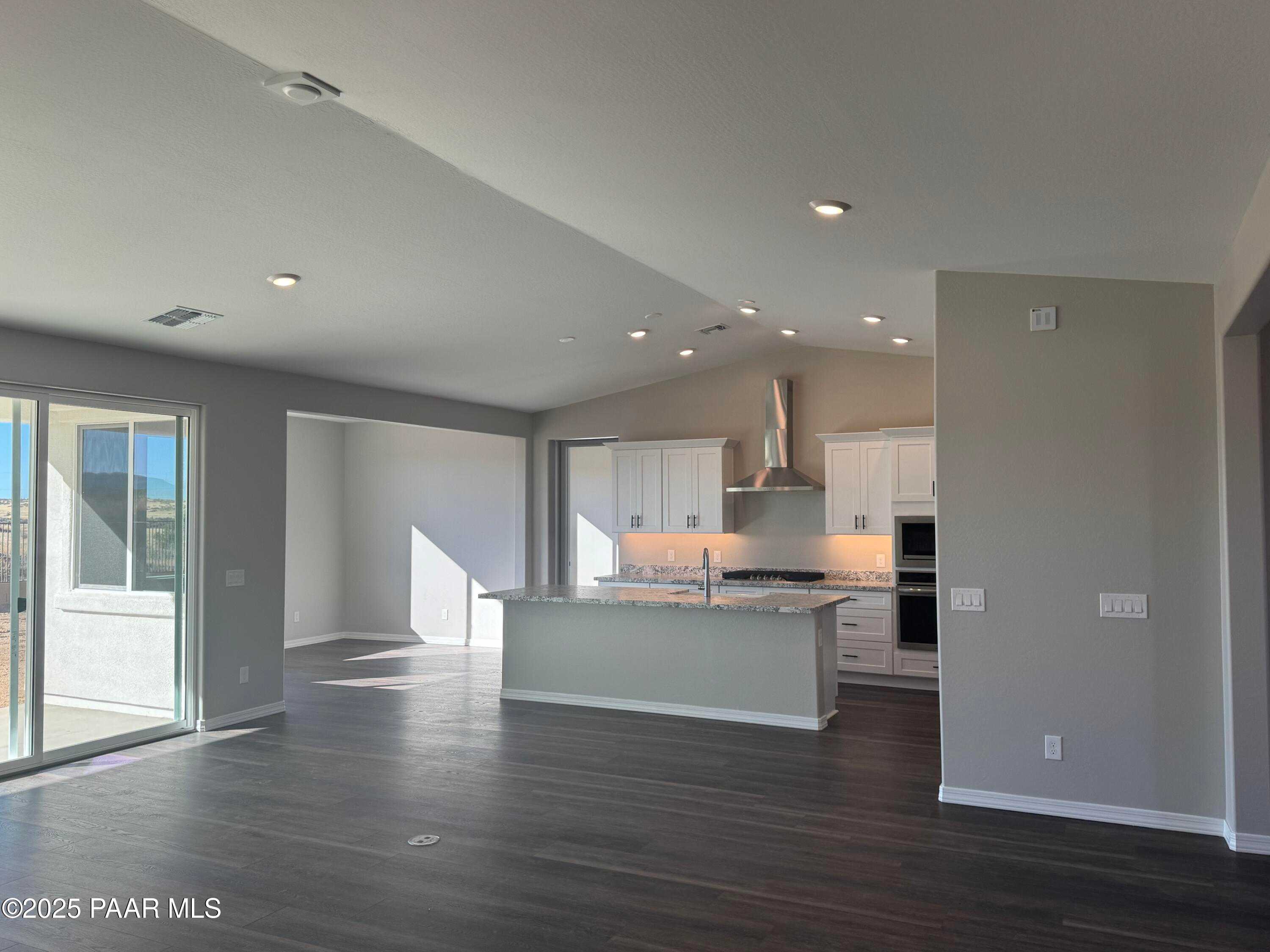 Modern open kitchen with white cabinets, large island sink, stainless appliances in The Monarch E, Westwood, Prescott, AZ