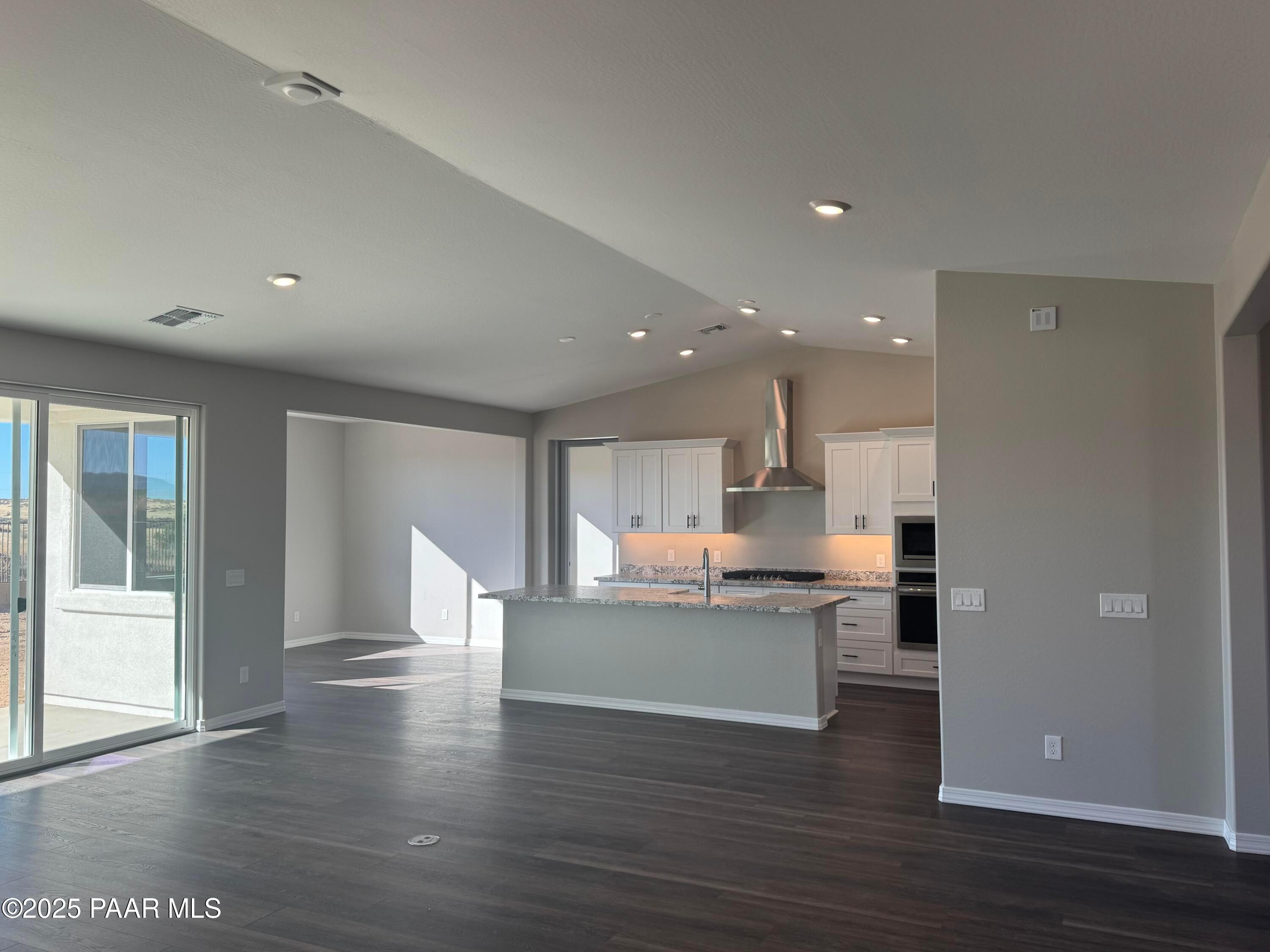 Modern open kitchen with white cabinets, large island sink, stainless appliances in The Monarch E, Westwood, Prescott, AZ
