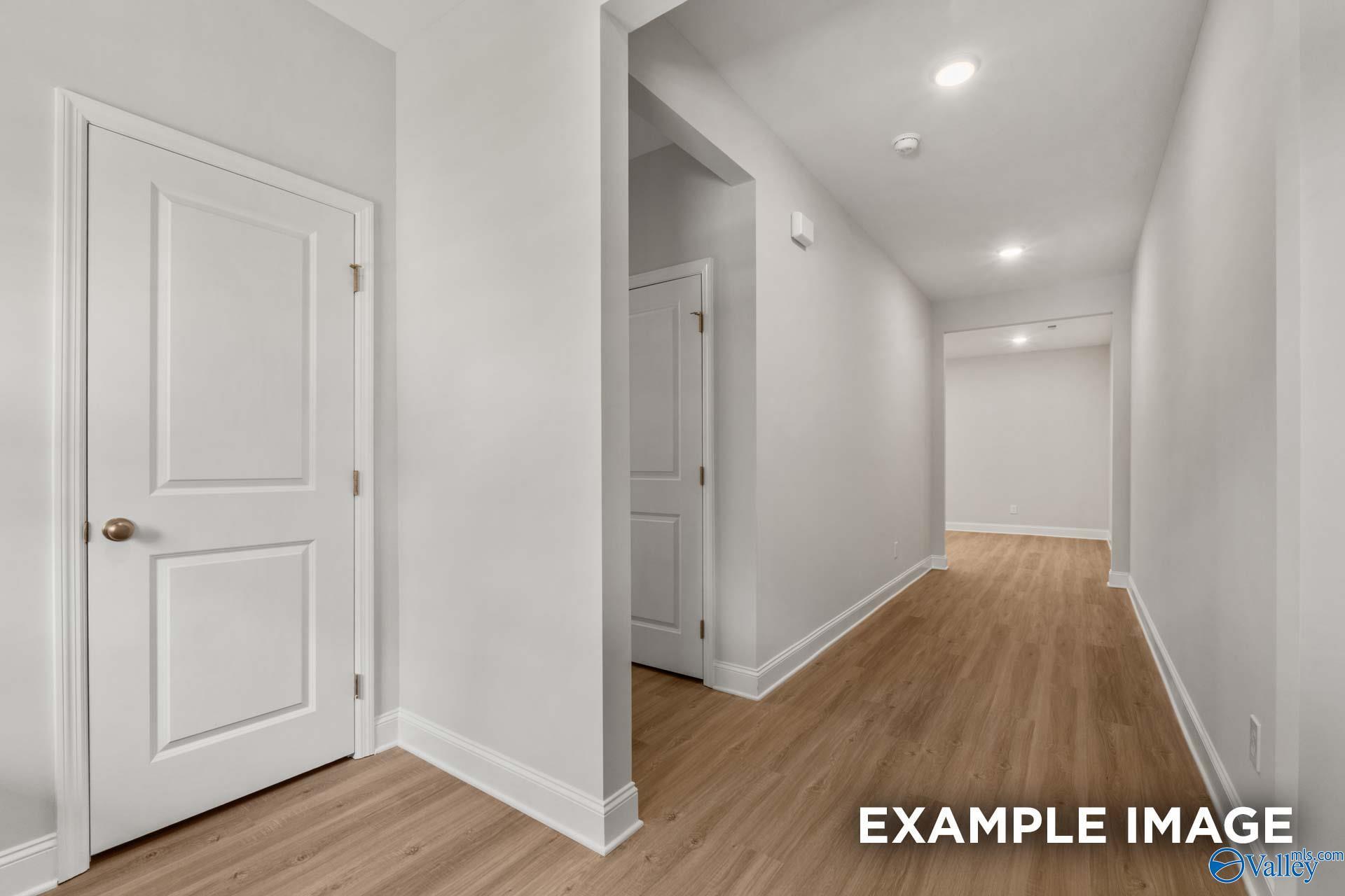 Bright hallway with white panel doors, luxury vinyl plank floors, and recessed lighting in Davidson Homes The Camilla C, Hartselle, Alabama