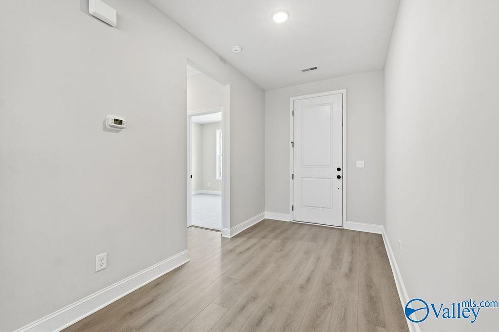 Bright hallway with light gray walls, white doors, and luxury vinyl plank flooring in The Montgomery B home, Hartselle, Alabama
