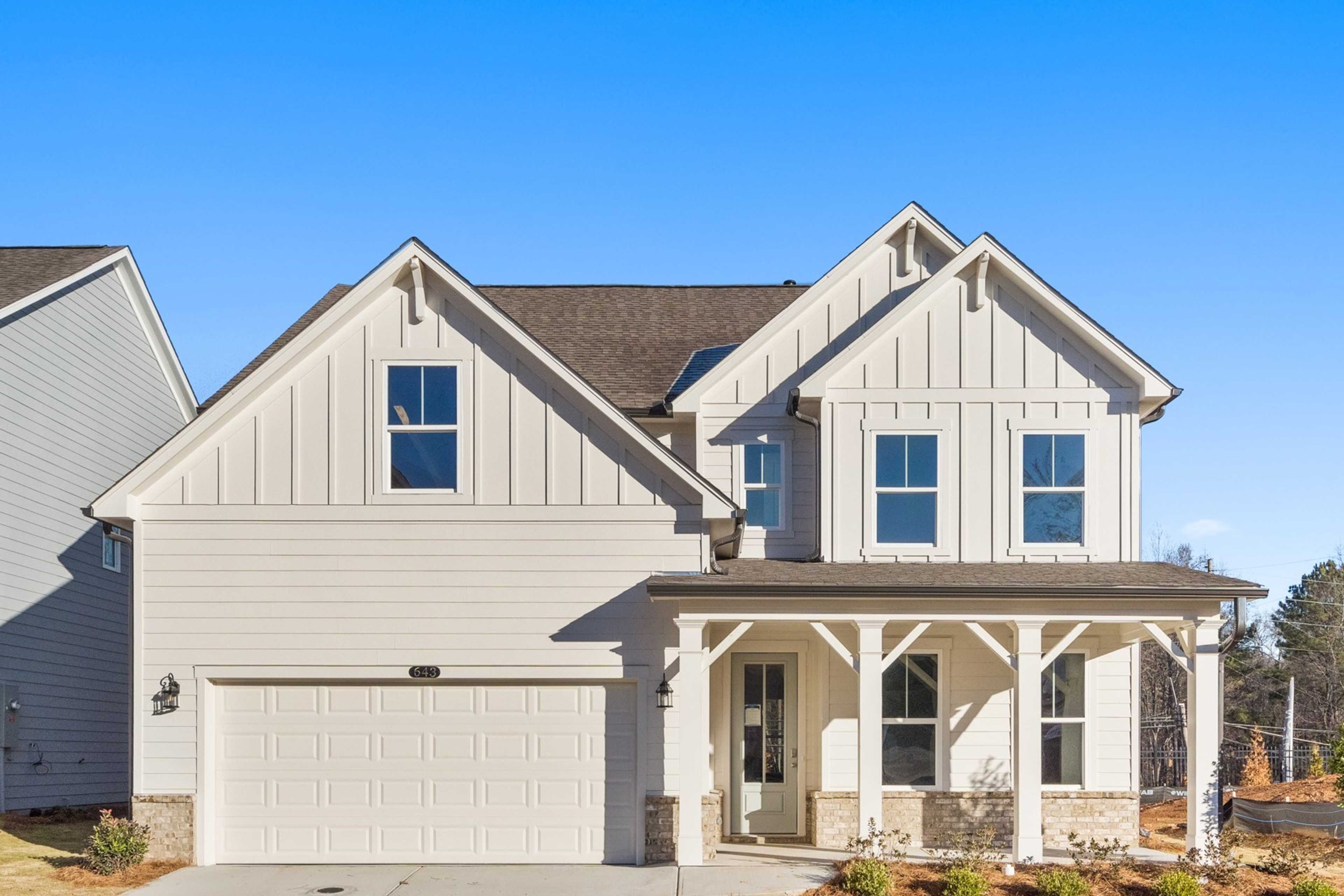 Modern board and batten home exterior at The Village at Shallowford in Kennesaw, Georgia with covered front porch and two-car garage