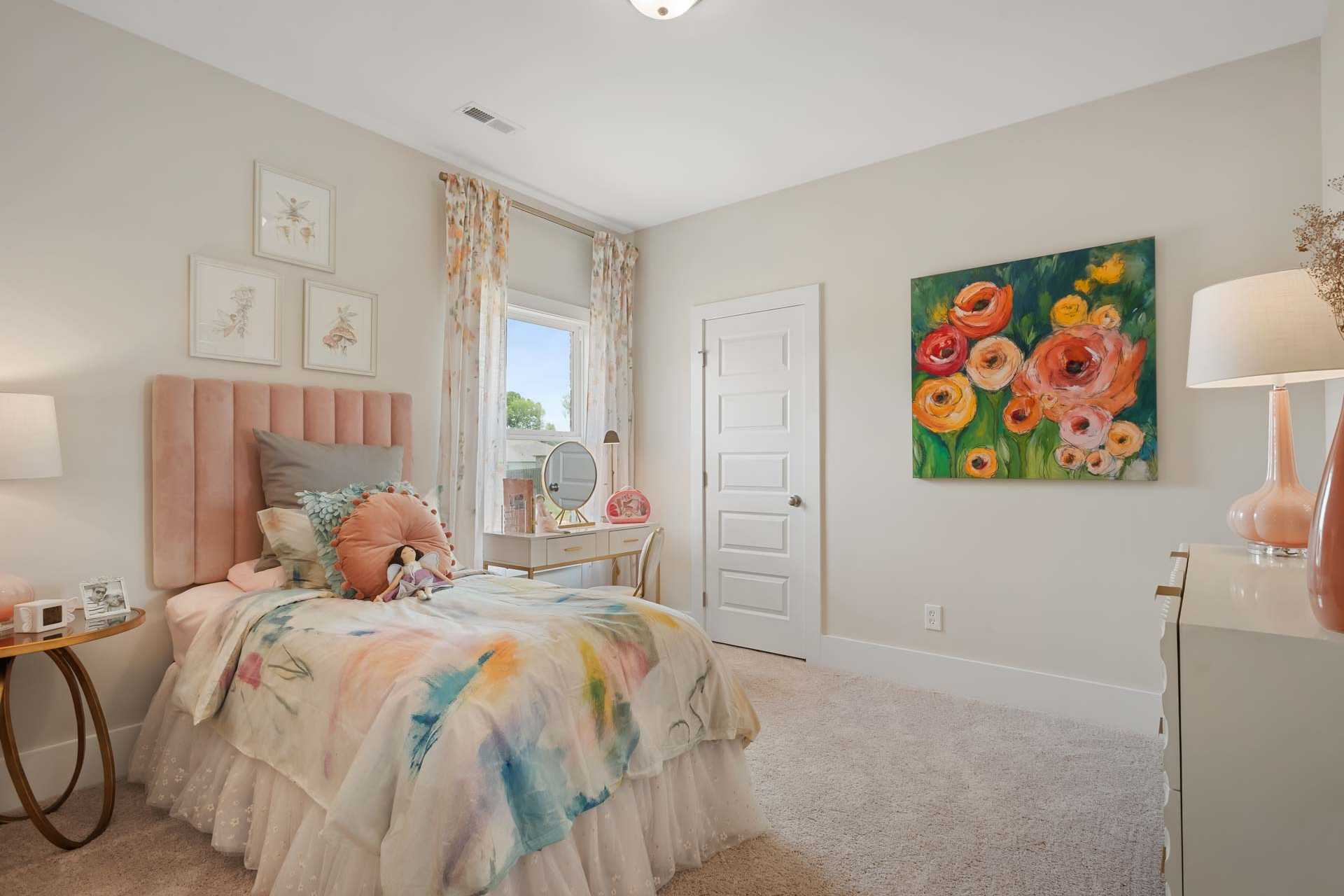 Cozy girl's bedroom at Flint Meadows in New Market Alabama with pink tufted bed, floral bedding, and vibrant flower artwork