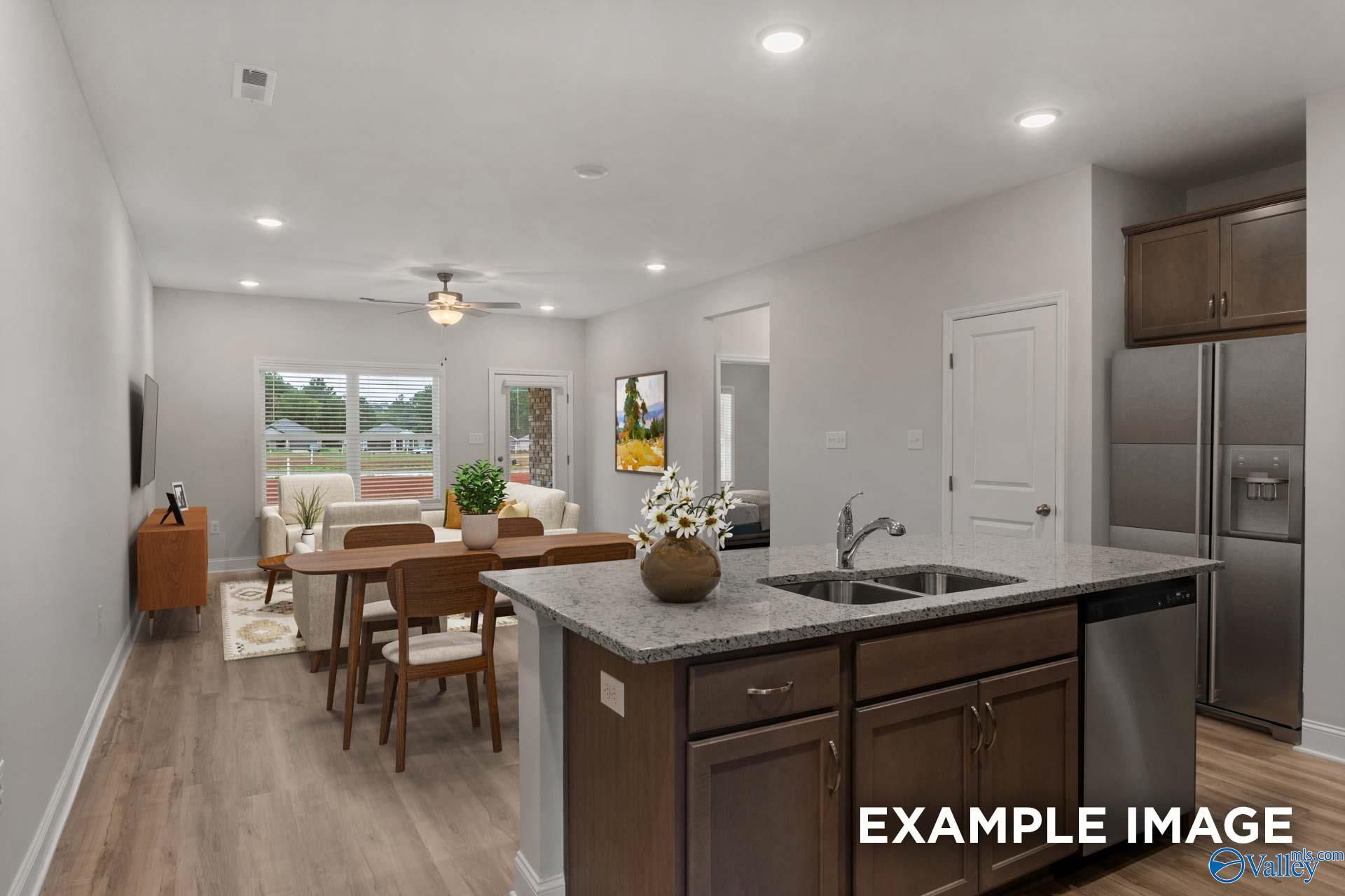 Spacious open-concept kitchen and living room with granite island, stainless appliances, and large windows in Davidson Homes The Cumberland B, Decatur, Alabama