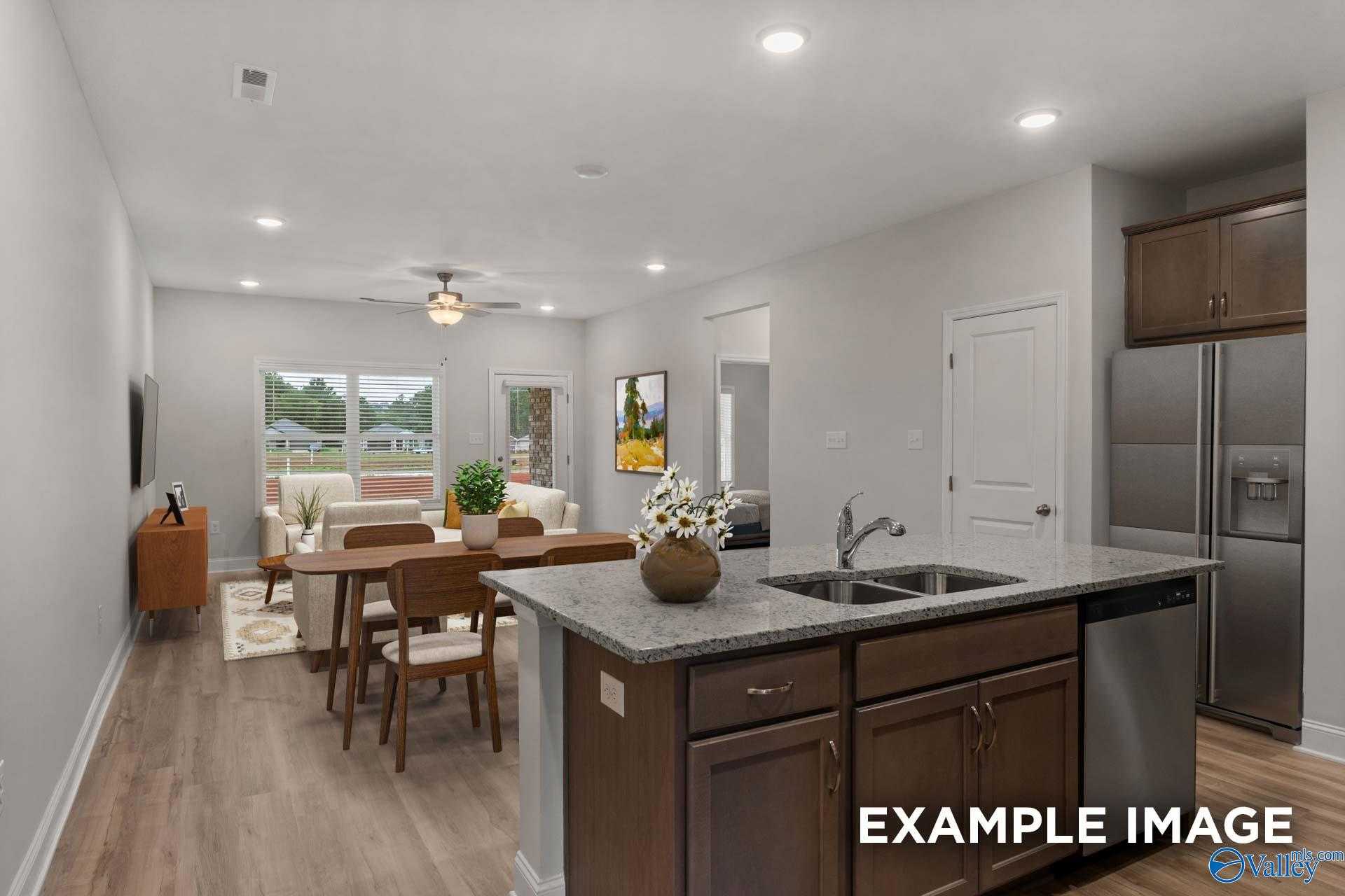 Spacious open-concept kitchen and living room with granite island, stainless appliances, and large windows in Davidson Homes The Cumberland B, Decatur, Alabama