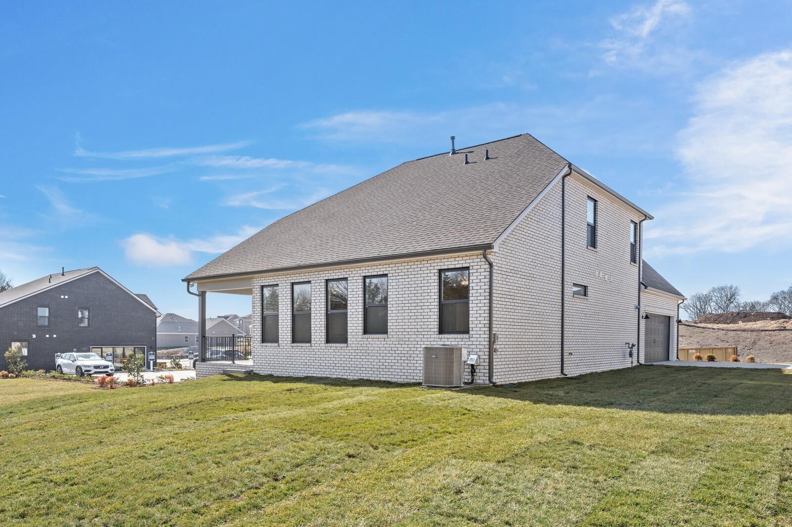 Modern 2-story brick home with 2-car garage, large windows, covered porch, and green yard in Benders Cove, Mt. Juliet - Davidson Homes The Ash C