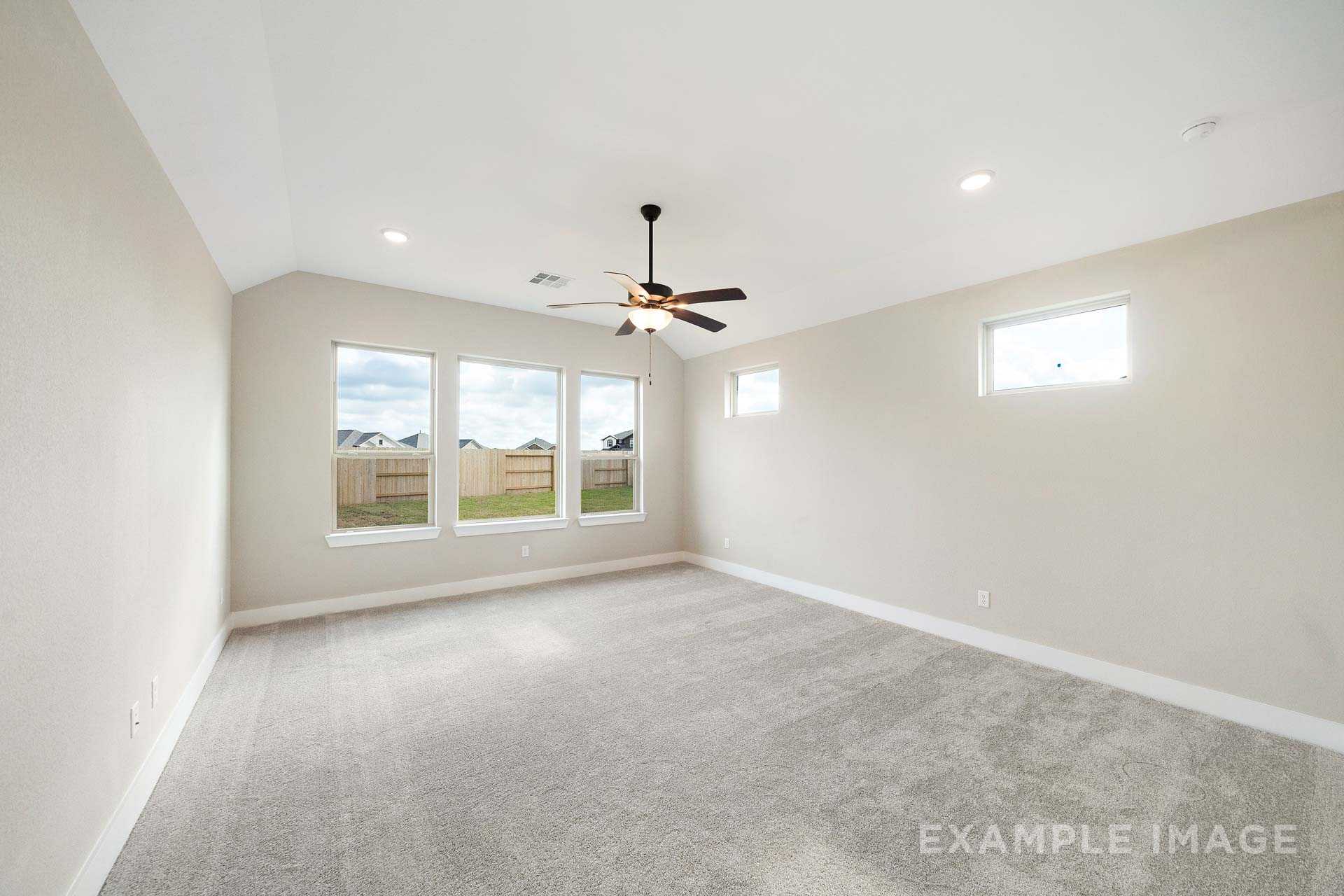 Spacious master bedroom in The Elizabeth A featuring large windows, ceiling fan, neutral beige walls, and plush carpet