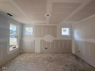 Unfinished room with tray ceiling and drywall in The Hickory II B floor plan at Woodland Crossing in Zebulon, North Carolina.