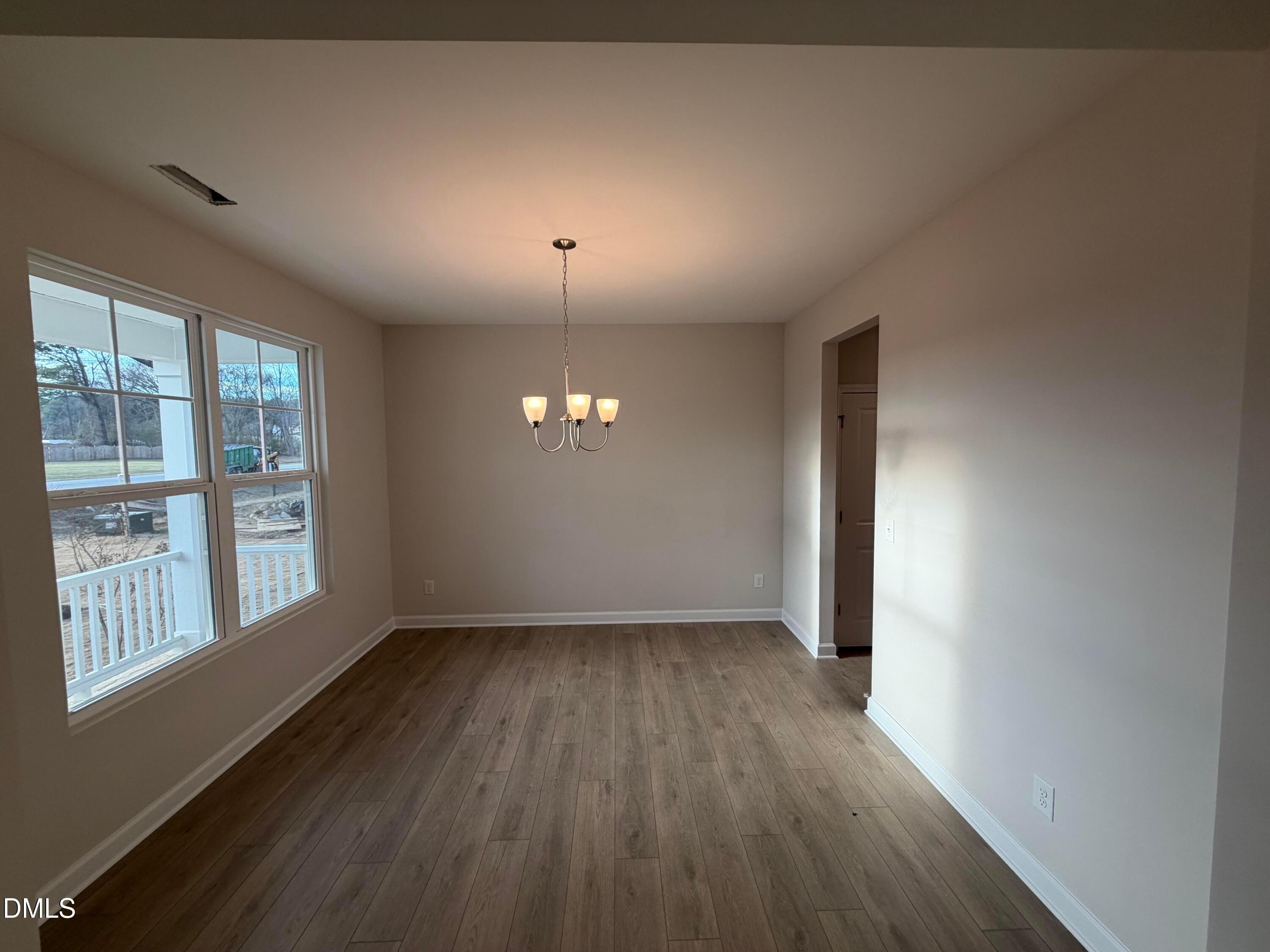 Spacious dining room with hardwood floors, large windows, and chandelier in Davidson Homes The Ash B, Lillington, NC