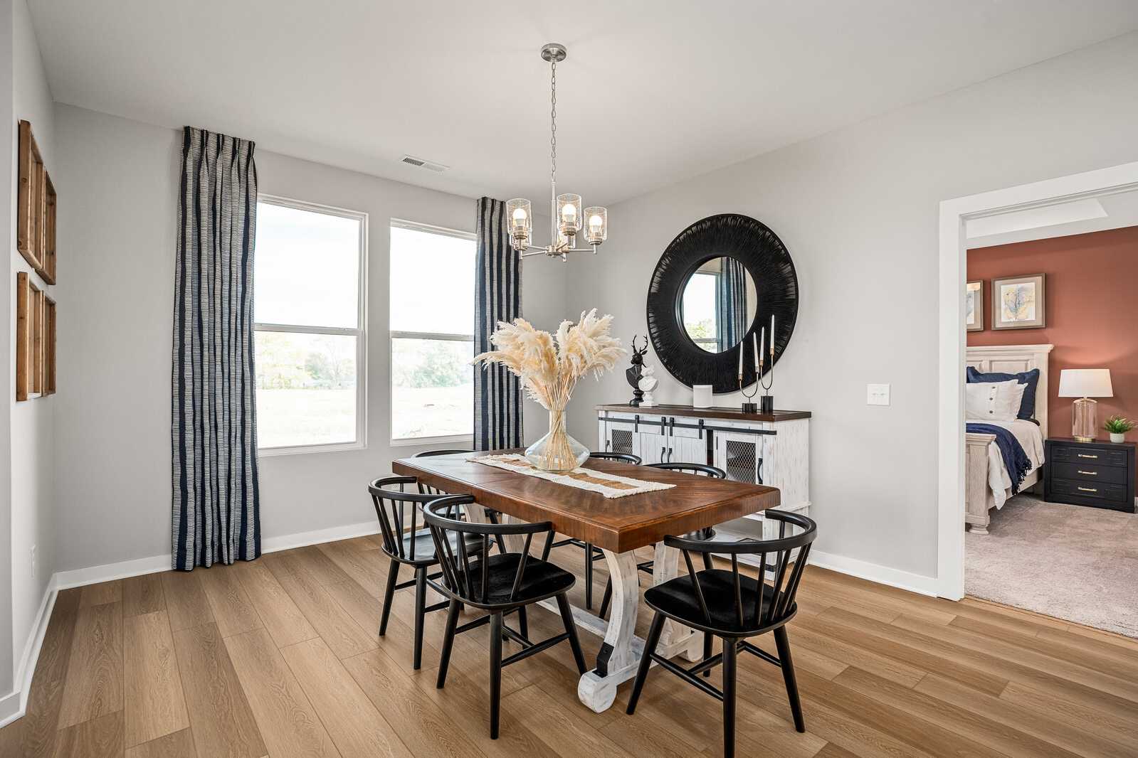Elegant dining room at Sage Farms in White House Tennessee with farmhouse table, black chairs, chandelier, round mirror, and pampas grass