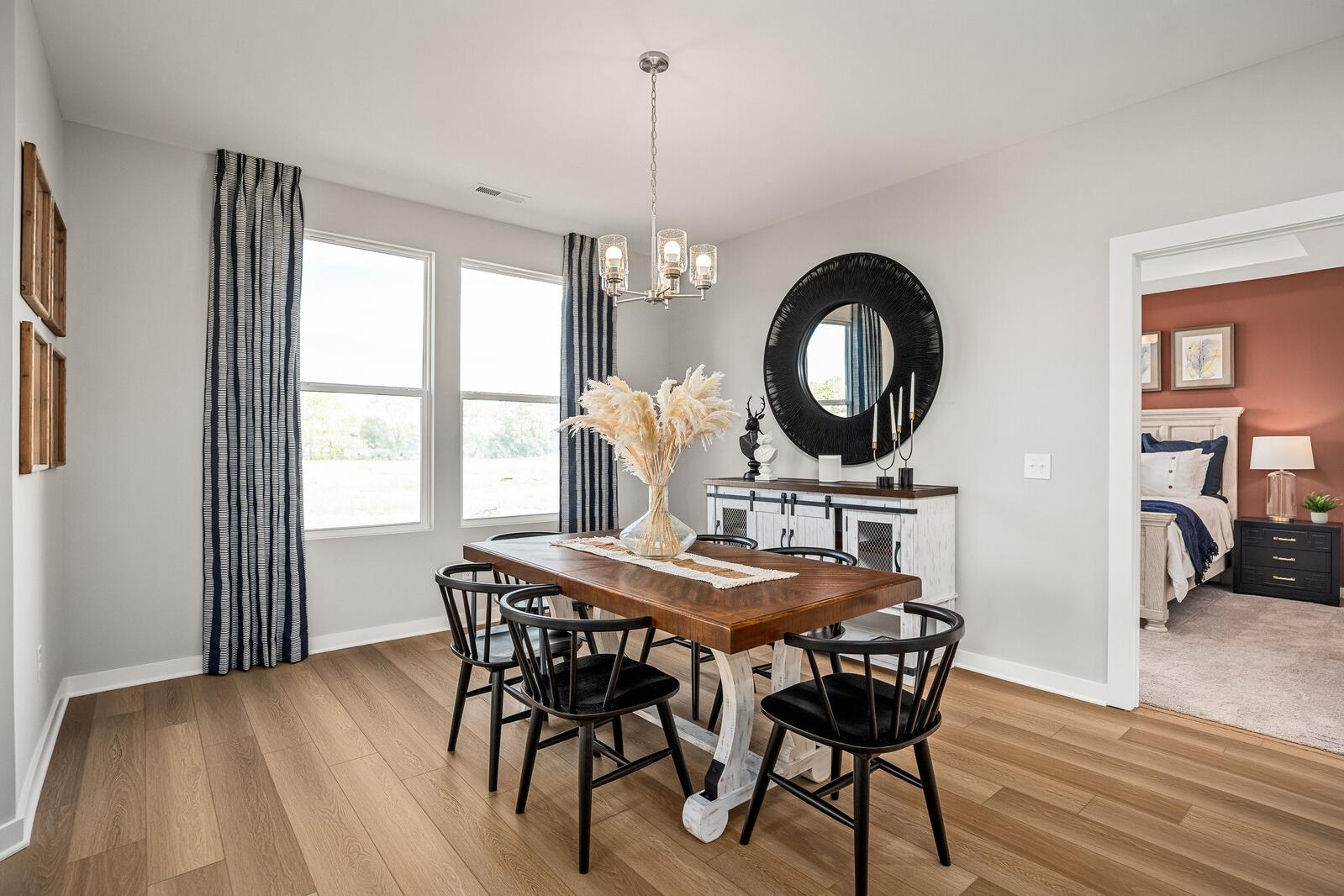 Elegant dining room at Sage Farms in White House Tennessee with farmhouse table, black chairs, chandelier, round mirror, and pampas grass