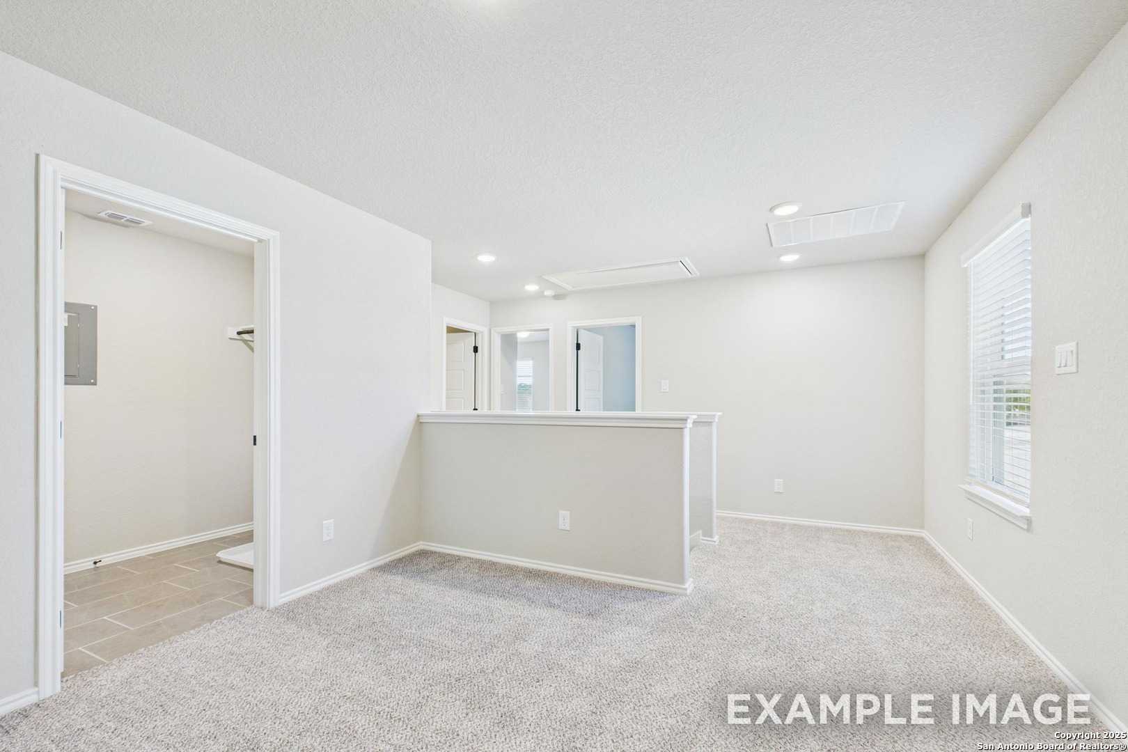 Bright upstairs loft with bar overlook, white walls, carpet flooring in Davidson Homes Charlotte A, San Antonio