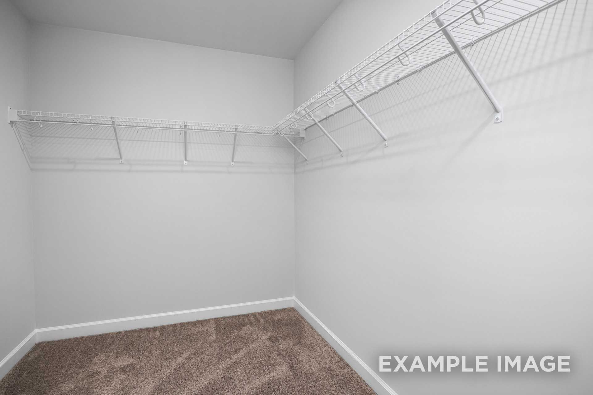Spacious walk-in closet in The Gavin C master suite featuring white wire shelving and beige carpet flooring