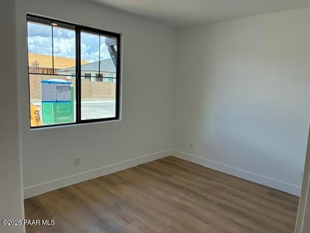 Empty bedroom with wood-look flooring and black-framed window in Davidson Homes Durango II G, Prescott, Arizona