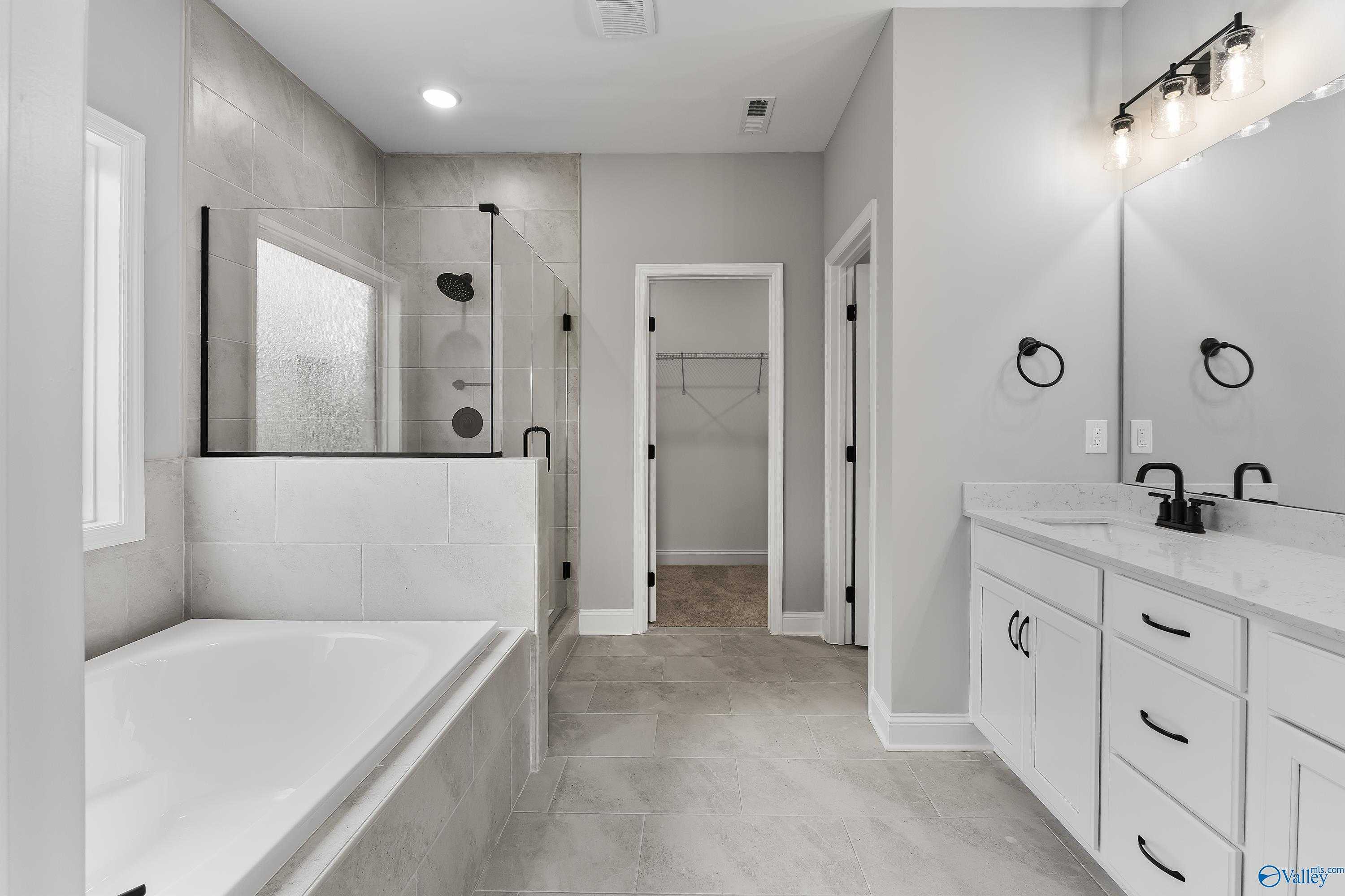 Modern master bathroom featuring freestanding tub, glass-enclosed shower, double vanity in Davidson Homes Montgomery B With Bonus, Toney AL