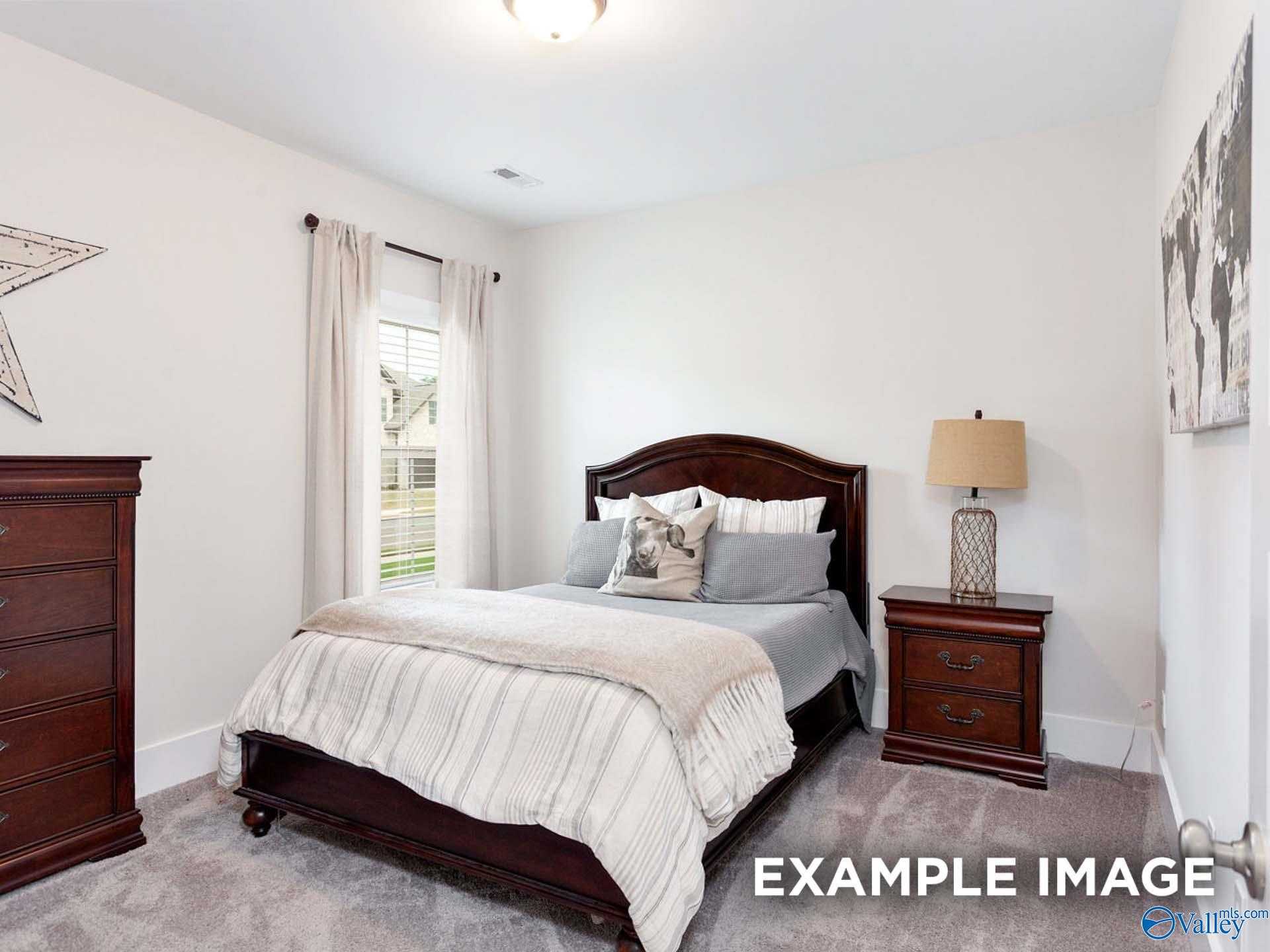 Cozy bedroom with queen bed, dark wood furniture, world map art in Davidson Homes The Finleigh, Meridianville, Alabama