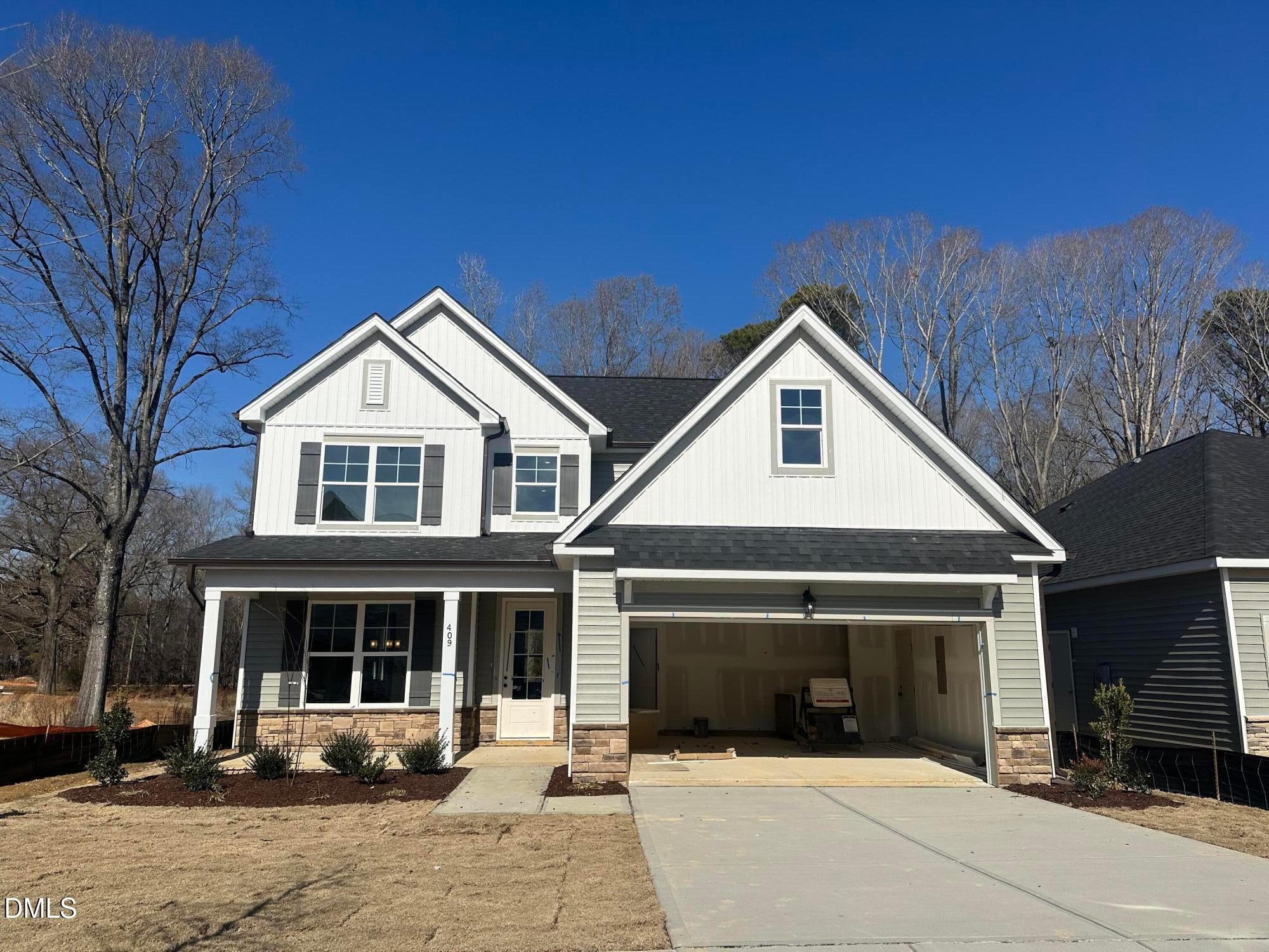 Two-story Ash B home by Davidson Homes with front porch, open 2-car garage, and brick accents in Woodland Crossing, Zebulon, NC