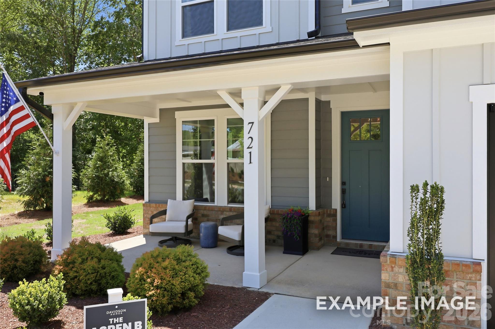 Covered front porch with seating and American flag at Davidson Homes The Aspen B in Windgate, Mooresville, North Carolina