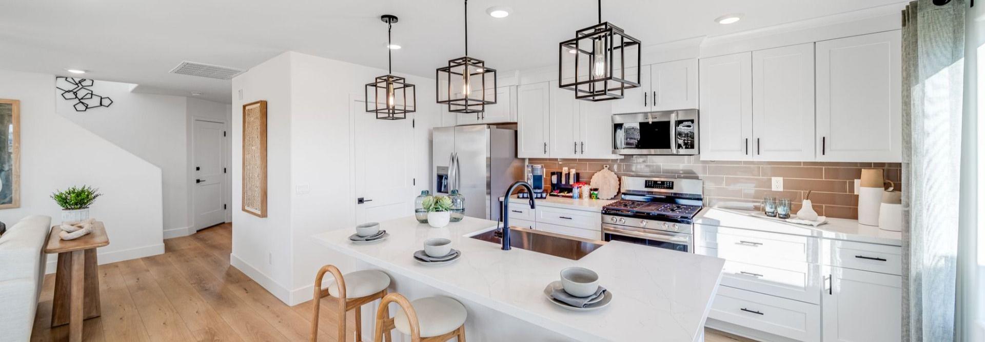 Spacious white kitchen at Senator Cottages in Prescott AZ with quartz island, bar stools, pendant lights, and stainless appliances