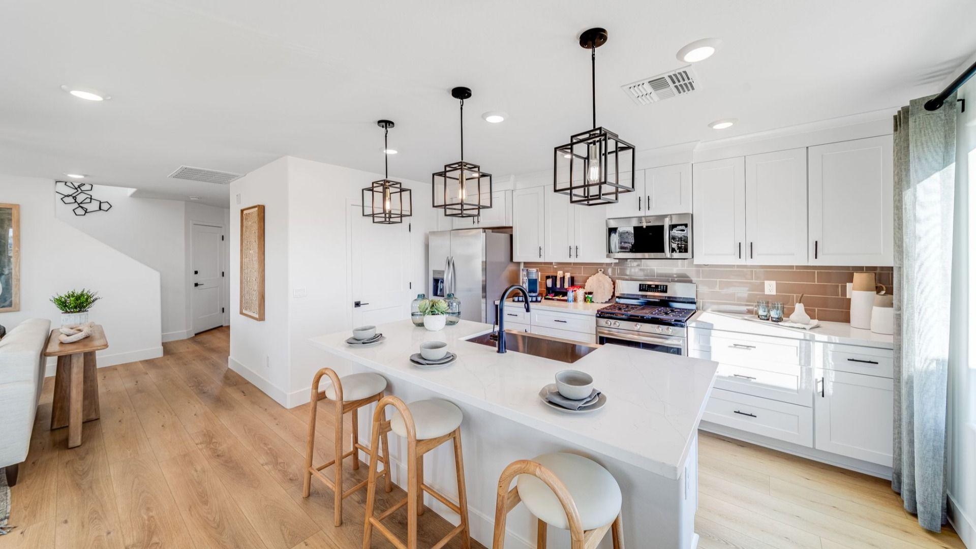 Spacious white kitchen at Senator Cottages in Prescott AZ with quartz island, bar stools, pendant lights, and stainless appliances