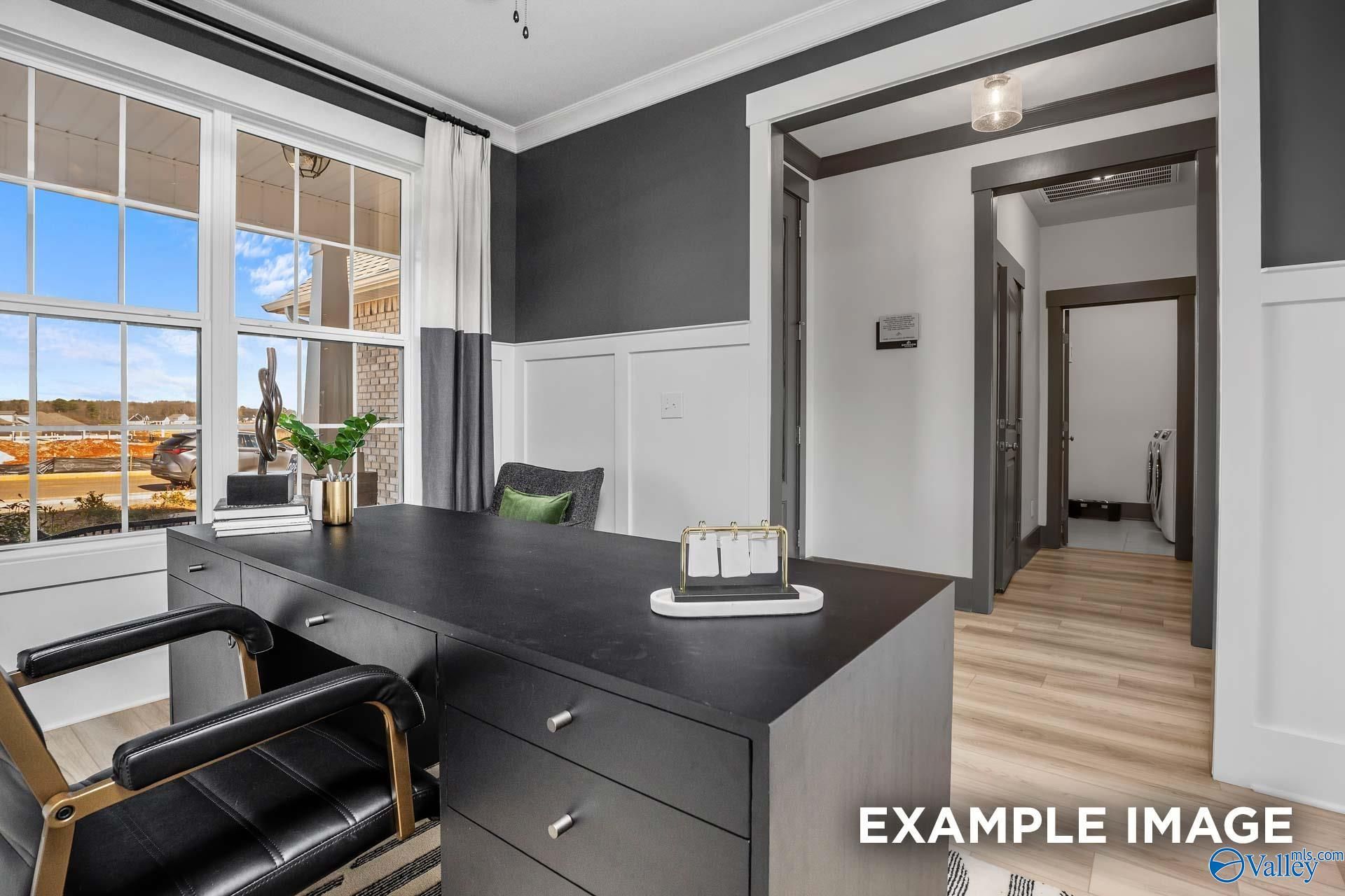 Modern home office with black desk, leather chairs, potted plants, and large windows in Davidson Homes The Rockford B, Madison, Alabama