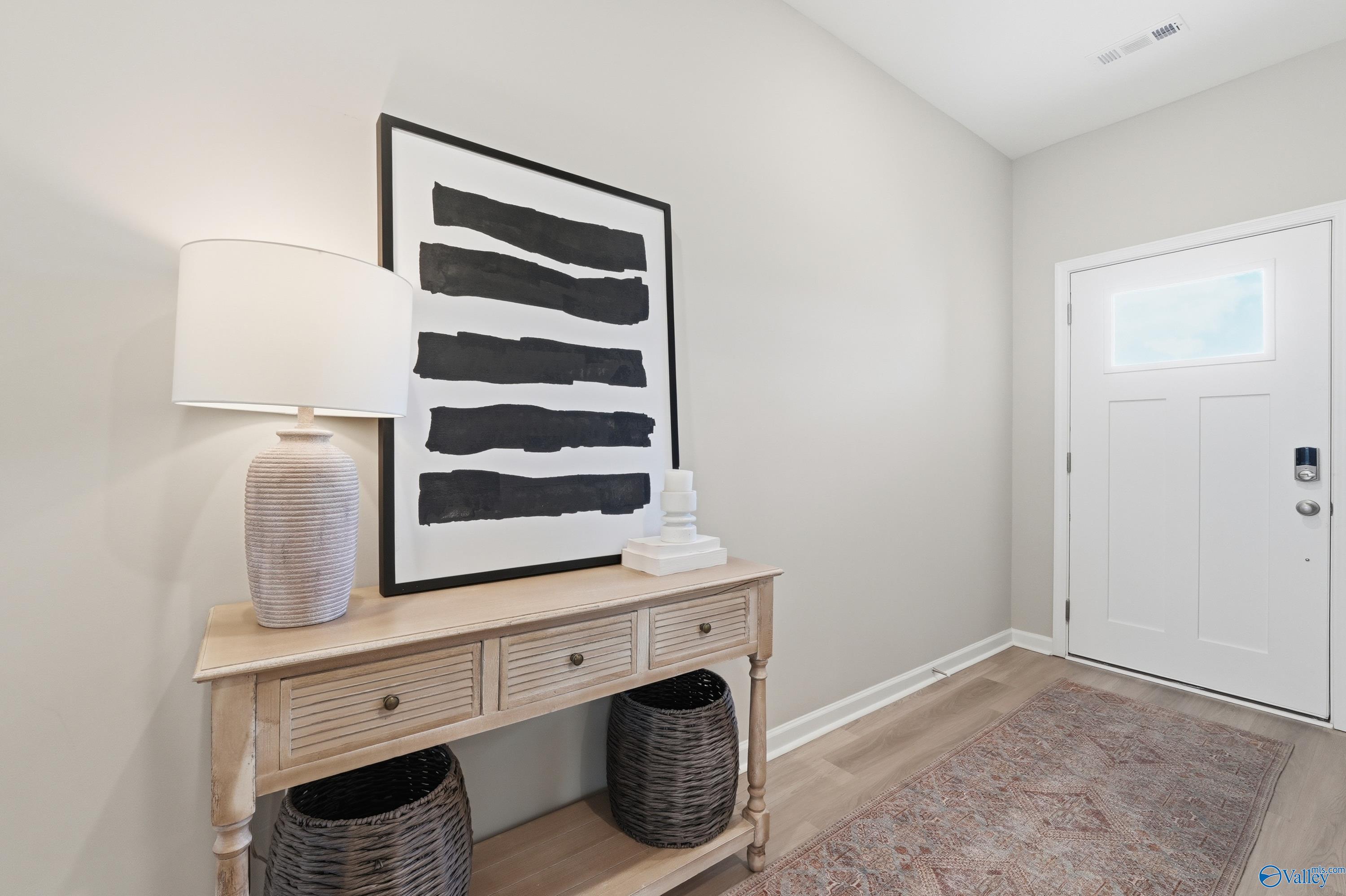 Elegant entry foyer with beige walls, console table, abstract black stripe art, and white door in Davidson Homes The Polaris, Fayetteville