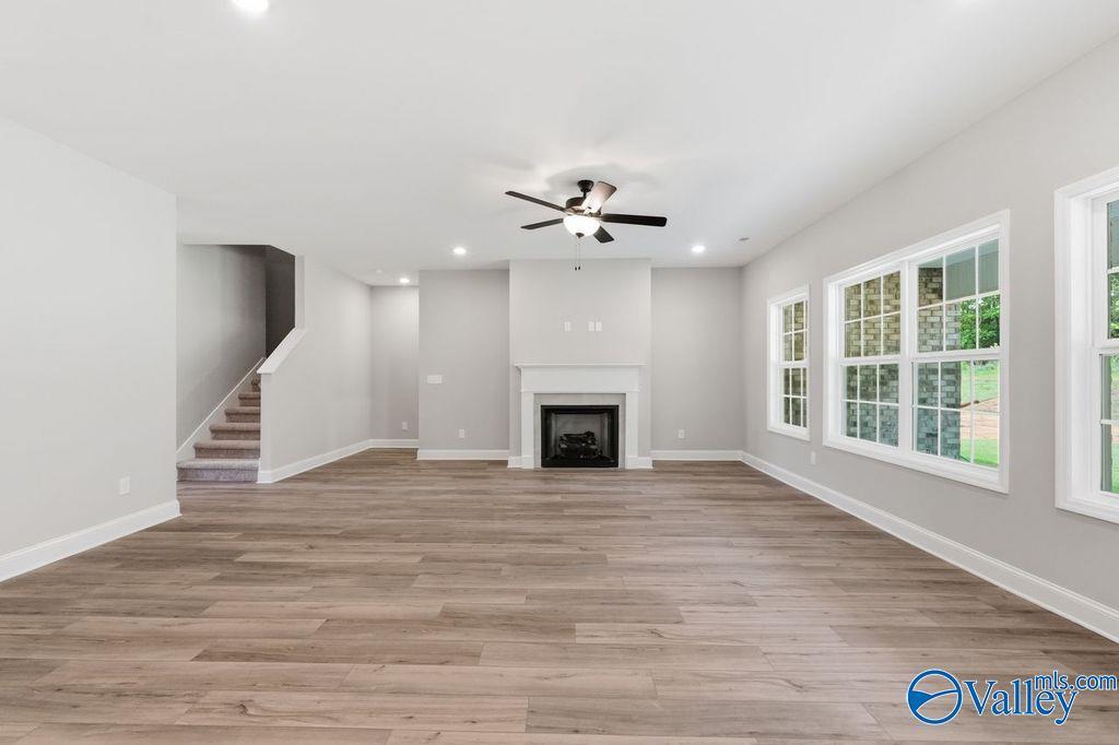 Spacious living room with fireplace and wood-look flooring in The Rockford floor plan at Cain Park, Hartselle, Alabama.