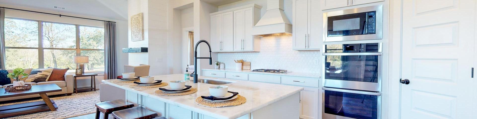Open-concept kitchen at Liberty Creek in Gallatin TN featuring white island, wood bar stools, stainless appliances, and hardwood floors