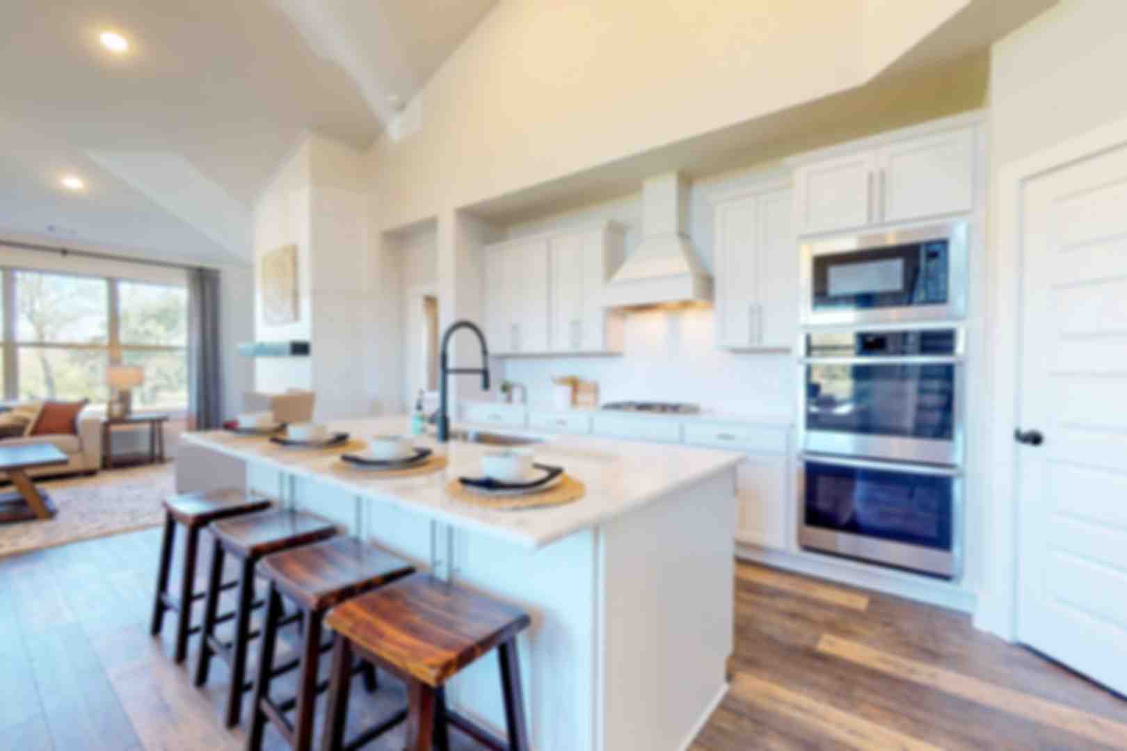 Open-concept kitchen at Liberty Creek in Gallatin TN featuring white island, wood bar stools, stainless appliances, and hardwood floors