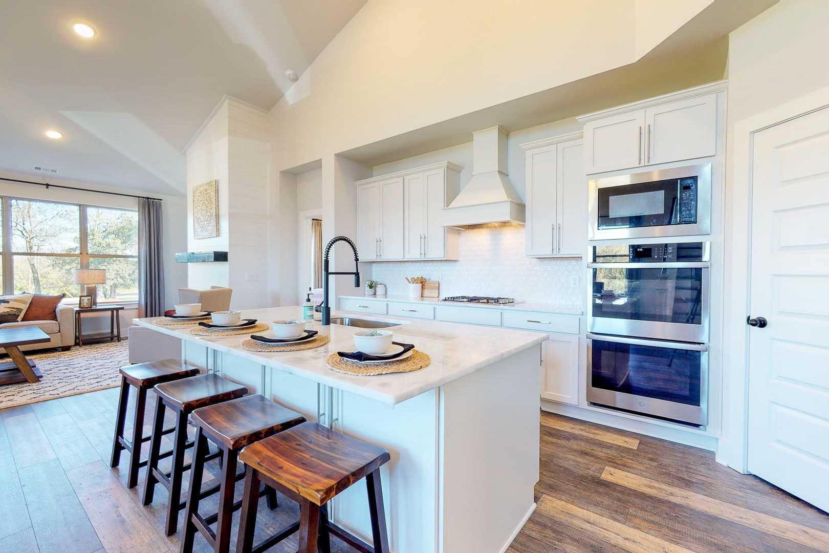Modern open-concept kitchen at Liberty Creek in Gallatin TN with white island, wooden stools, stainless appliances, and hardwood floors