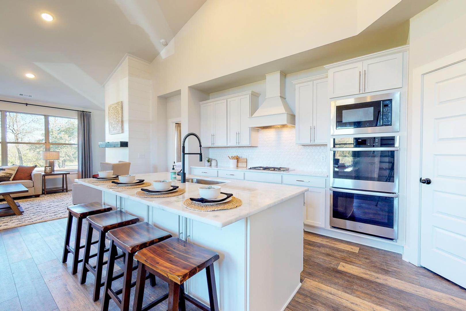 Modern open-concept kitchen at Liberty Creek in Gallatin TN with white island, wooden stools, stainless appliances, and hardwood floors