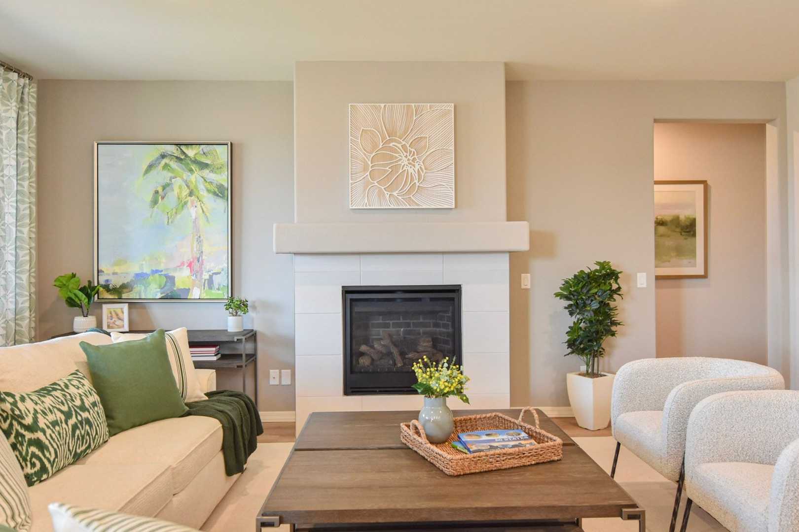 Spacious living room in The Harmony by Davidson Homes featuring beige sofa, gas fireplace, tropical palm art, and potted plants
