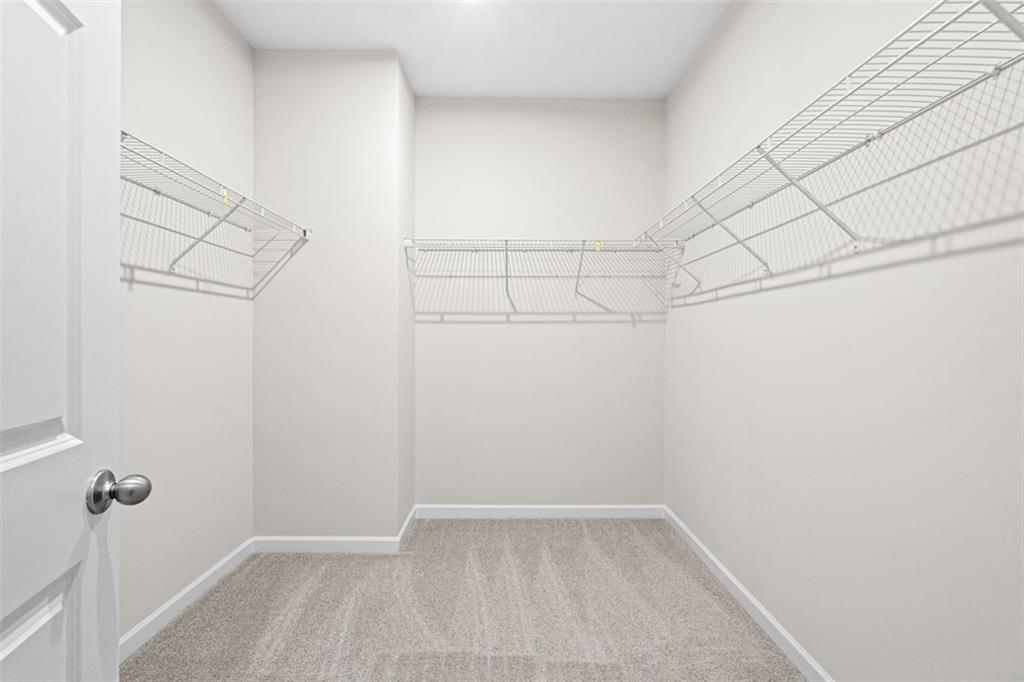 Spacious walk-in closet with wire shelving and beige carpet in Davidson Homes The Glenwood C at Wehunt Meadows, Hoschton