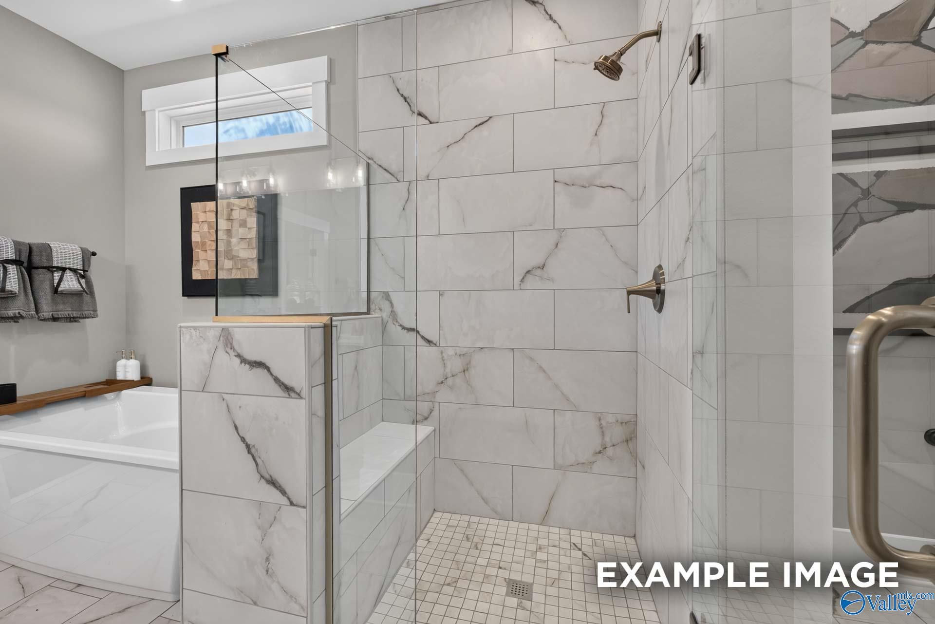 Marble-tiled walk-in shower with glass panel and soaking tub in master bath at The Ashport K, Forest Glen, Hazel Green