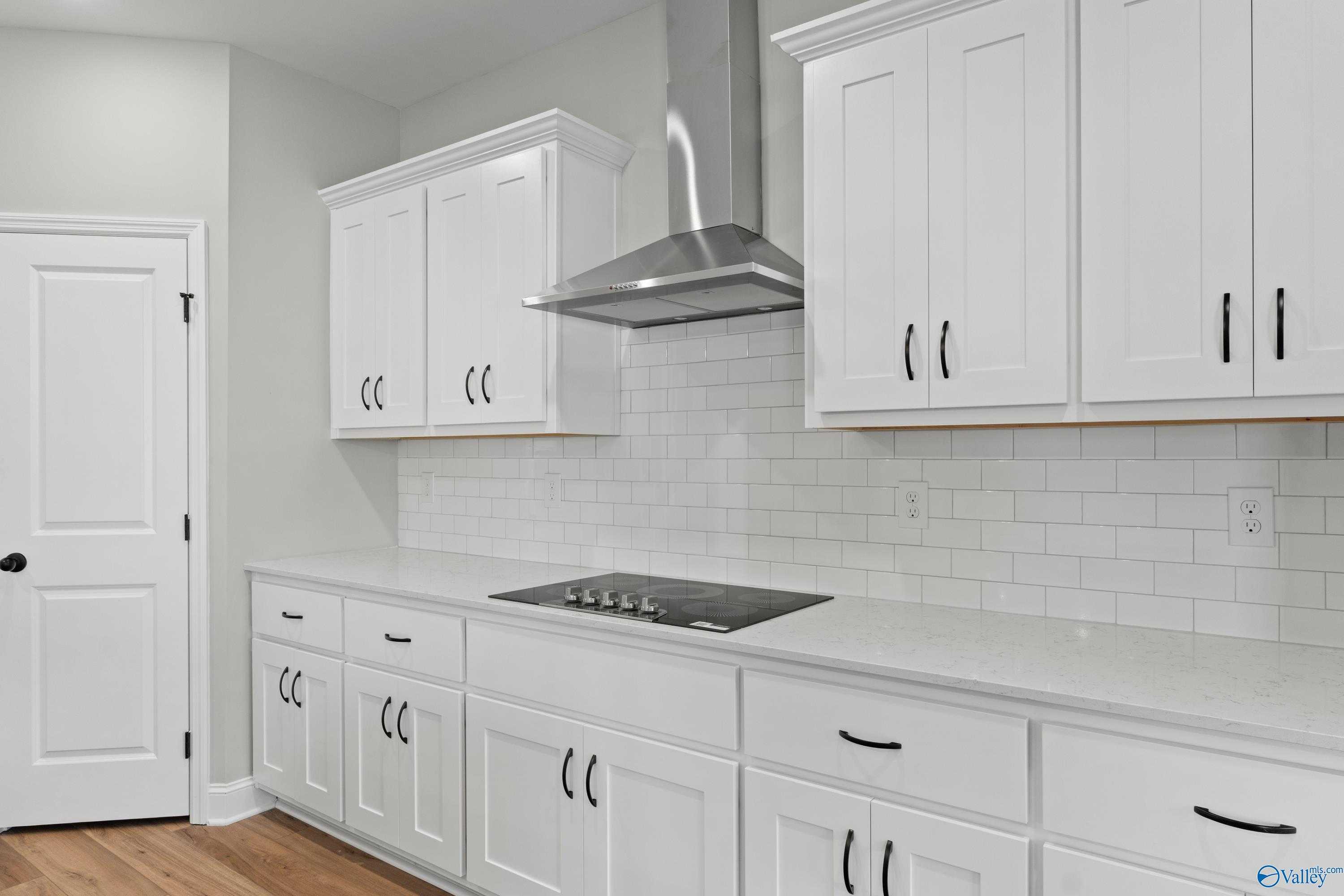 Modern white shaker kitchen with stainless hood, subway tile backsplash, quartz counters in Davidson Homes The Rockford, Toney, Alabama