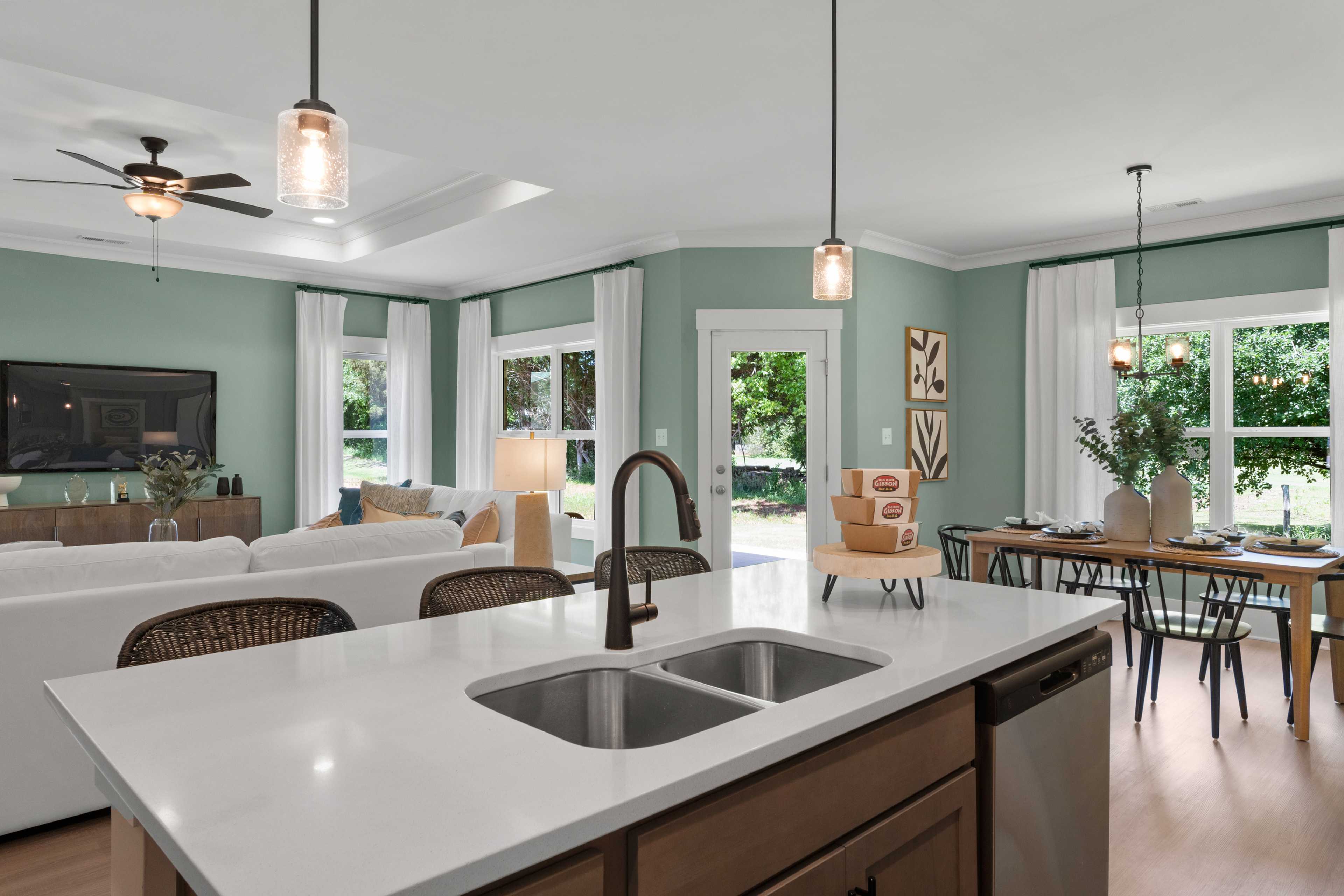 Open-concept kitchen and living room at Hollon Meadow in Decatur AL with white island, hardwood floors, sage walls, and large windows