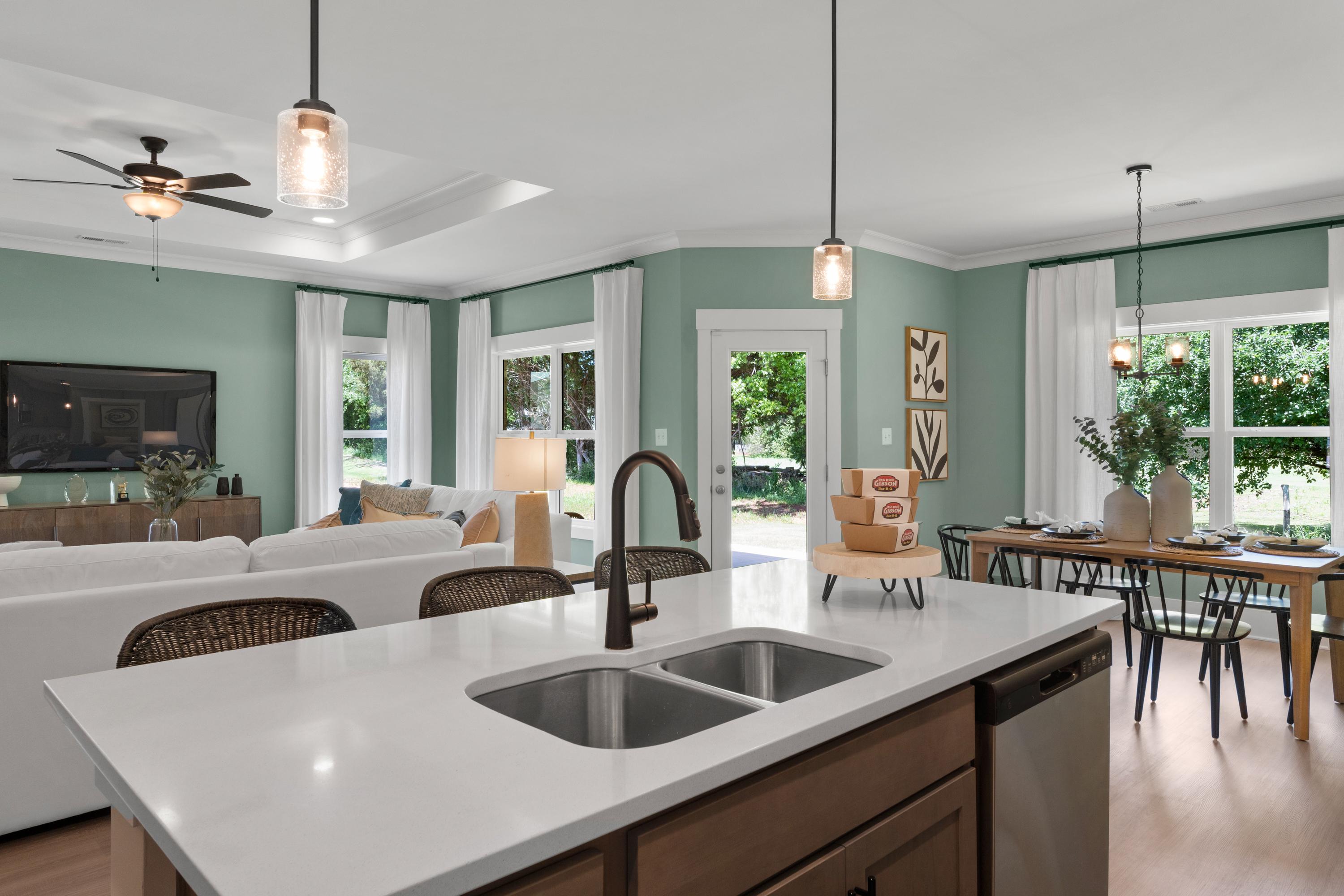 Open-concept kitchen and living room at Hollon Meadow in Decatur AL with white island, hardwood floors, sage walls, and large windows