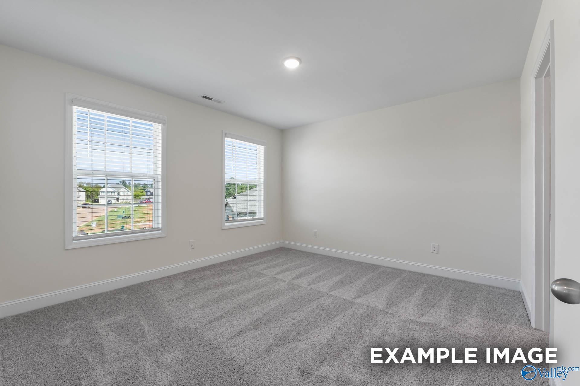 Bright secondary bedroom with large windows, beige walls, and gray carpet in The Shelby A, Hazel Green, Alabama