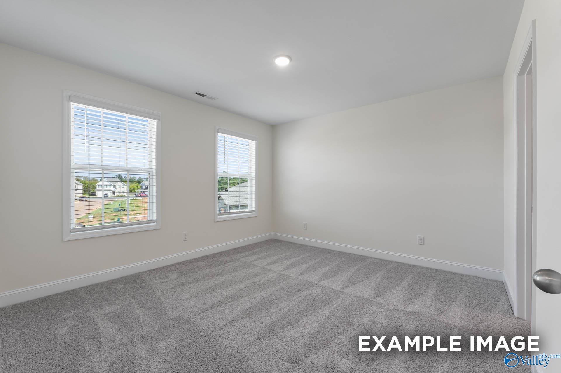 Bright secondary bedroom with large windows, beige walls, and gray carpet in The Shelby A, Hazel Green, Alabama